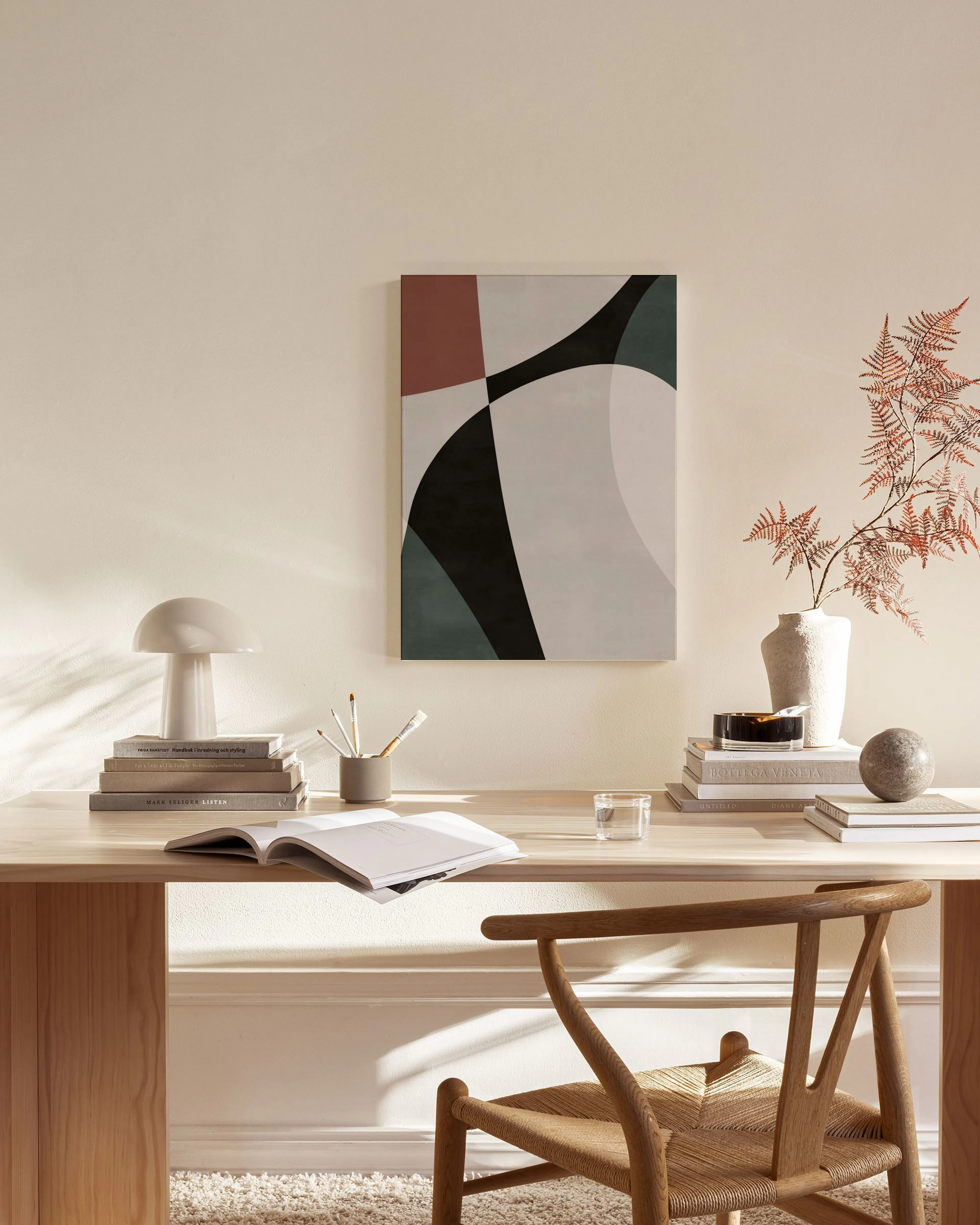 Toile abstraite aux formes géométriques bordeaux, vert foncé et gris, suspendue dans un salon moderne.