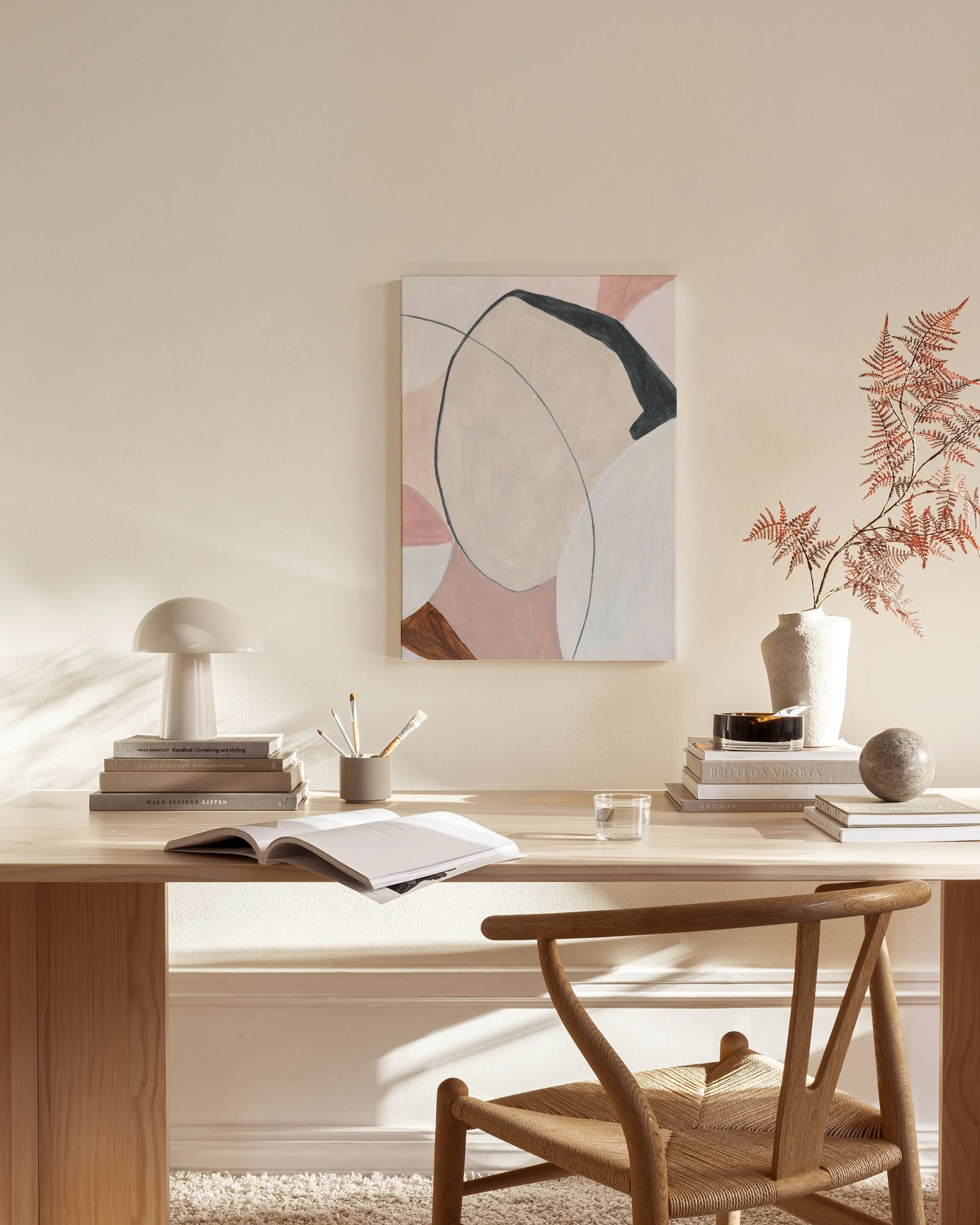 Abstract canvas print with organic shapes in blush pink, white, black, and brown, hanging in a modern living room.