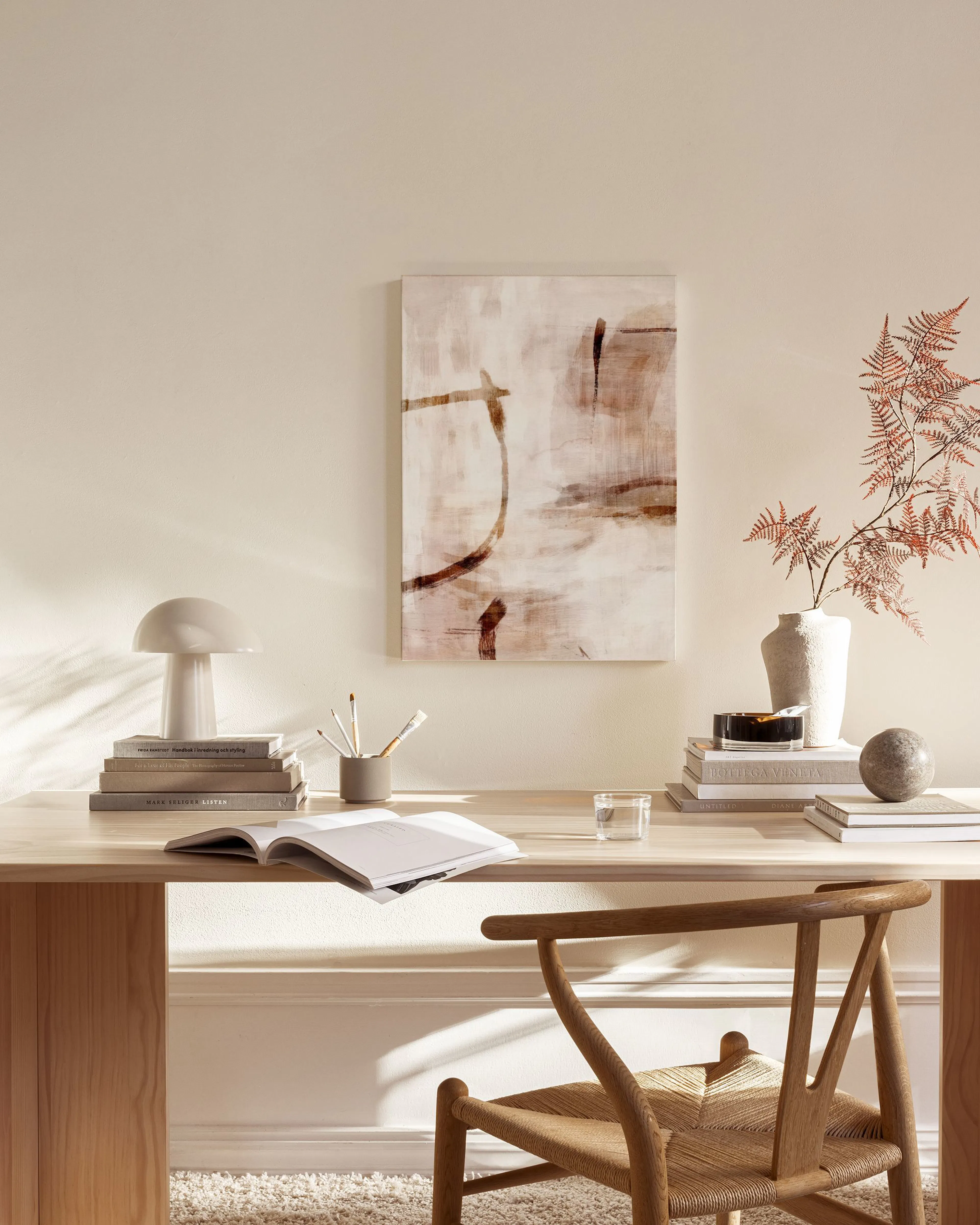 Abstract canvas print with warm beige, brown, and off-white tones, featuring organic lines, hanging in a minimalist living room.