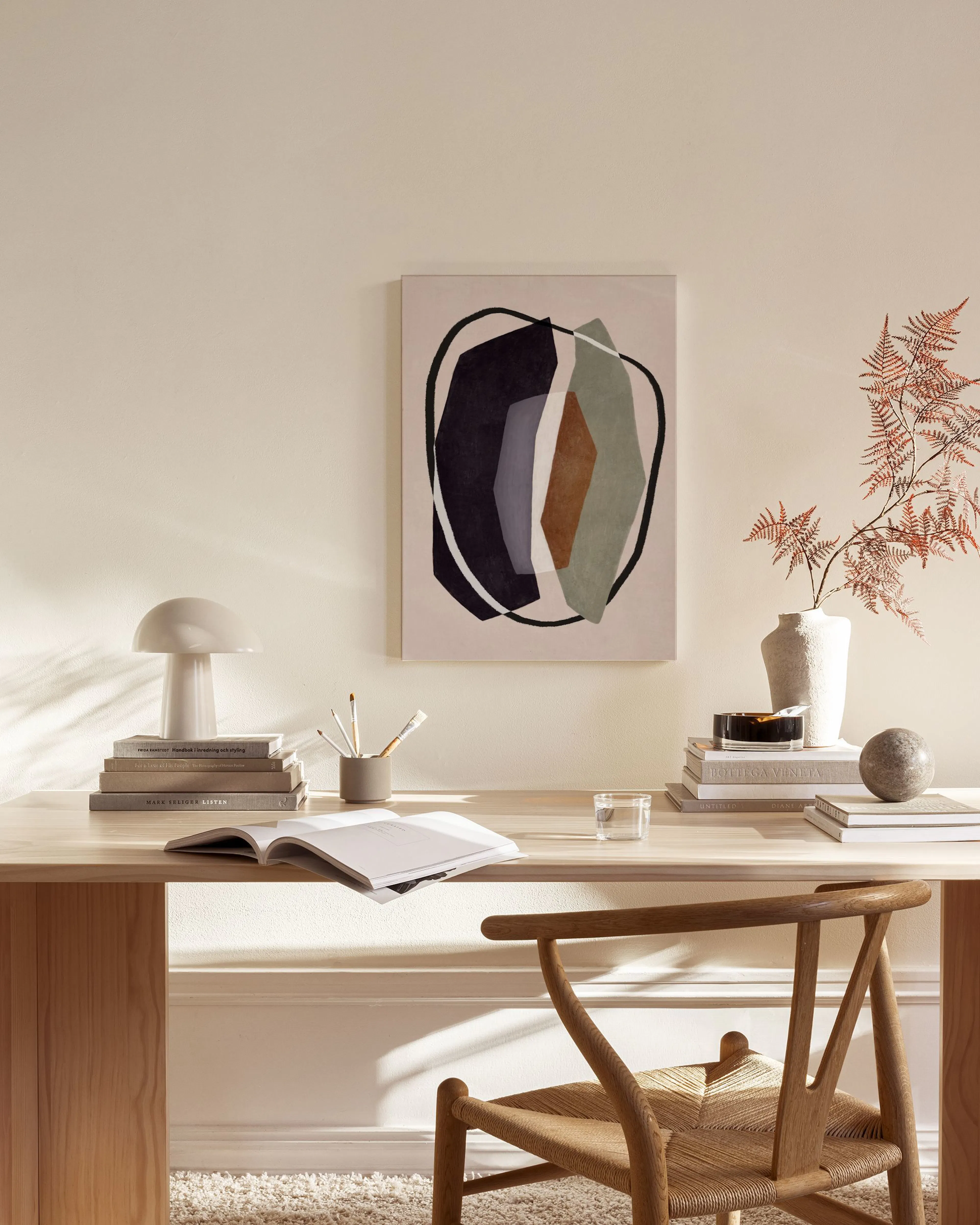 Abstract canvas print with dark, grey, and brown organic shapes outlined in black, hanging in a minimalist living room.