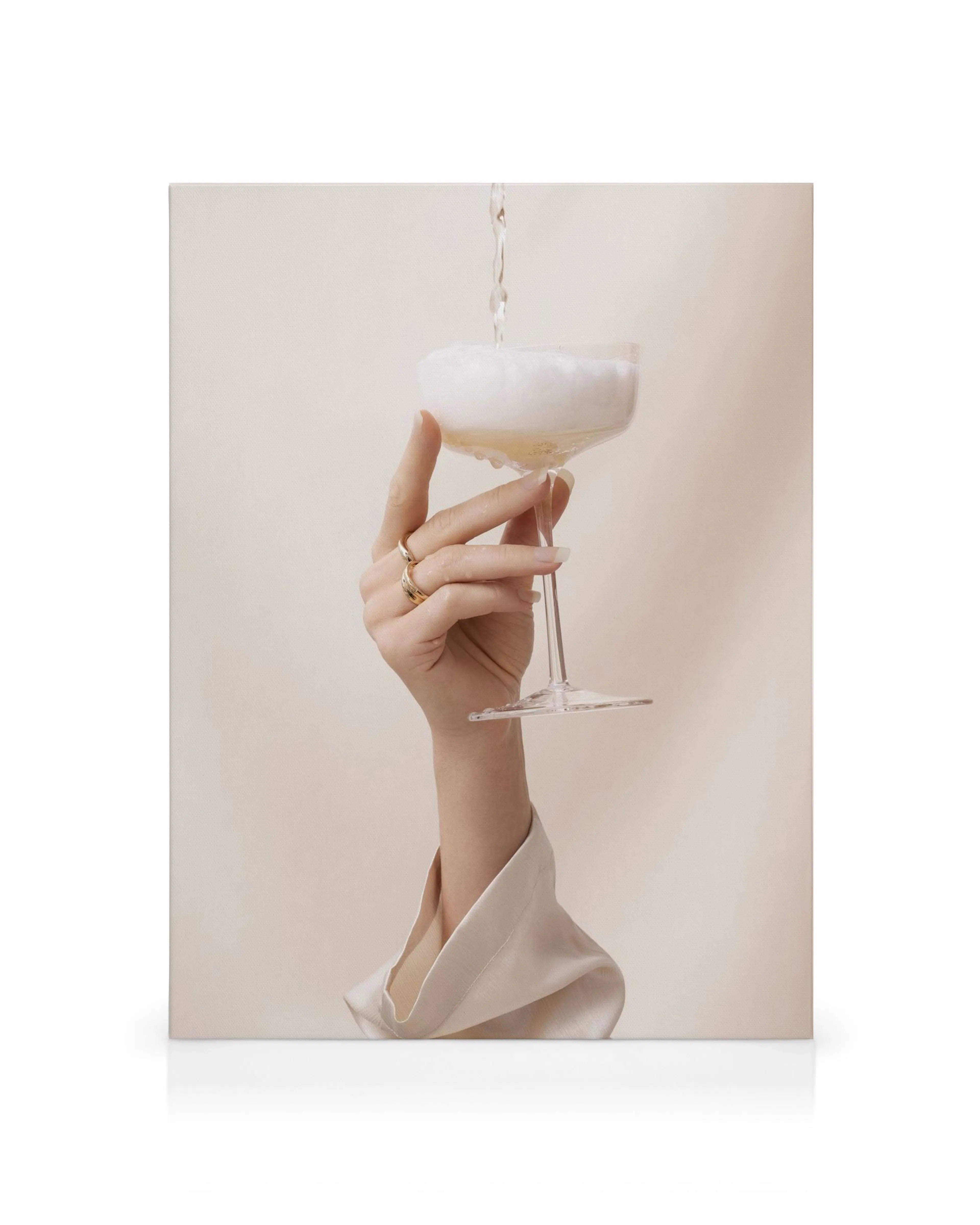 Leinwandbild: Hand hält Sektglas, Champagner wird eingegossen, Schaum, beige