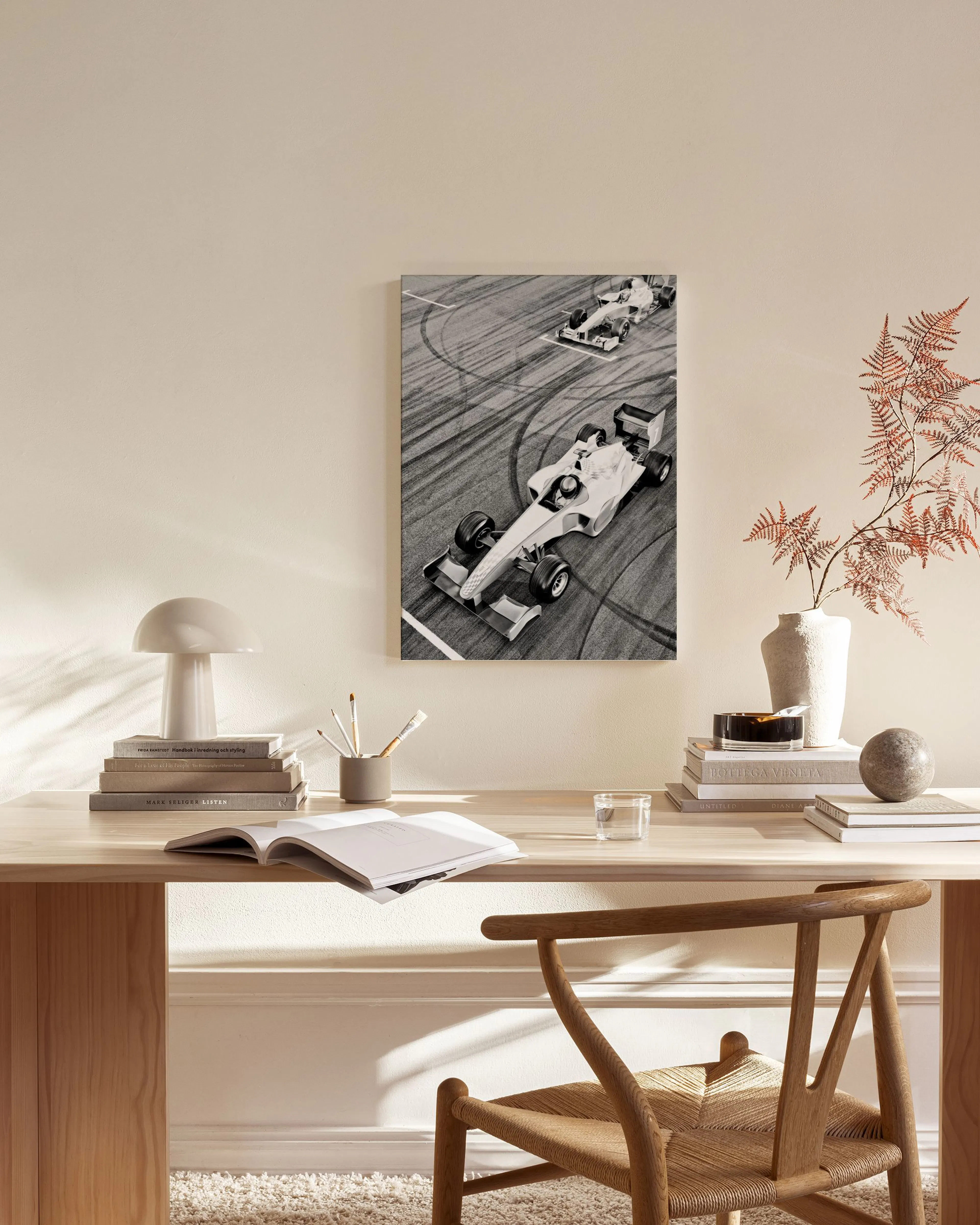 Zwart-wit canvas van twee Formule 1-wagens op een circuit, hangend in een neutrale woonkamer boven een houten dressoir.