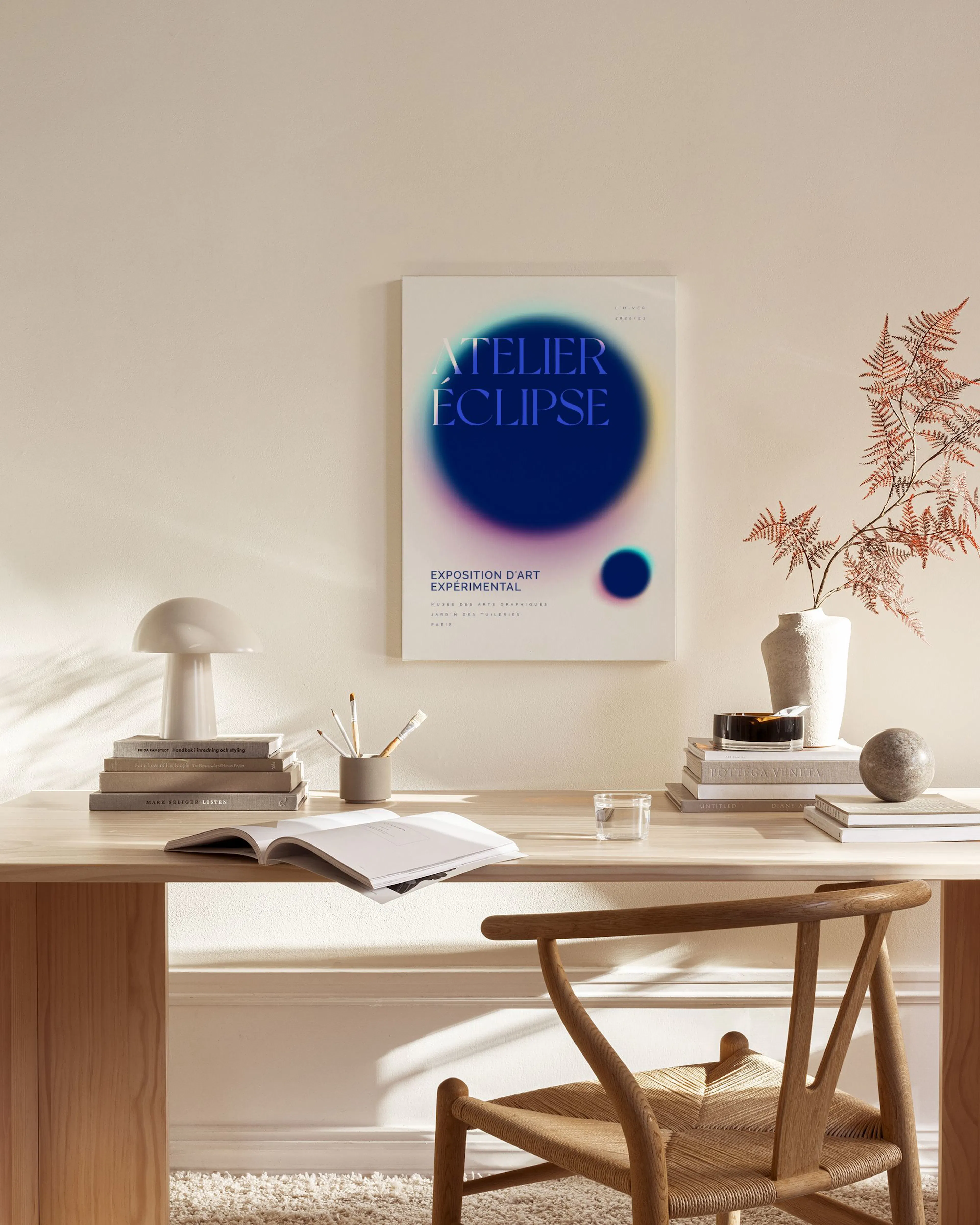 Lærred med en plakat i blålilla nuancer med teksten ATELIER ÉCLIPSE, hængende i en stue over et træmøbel.