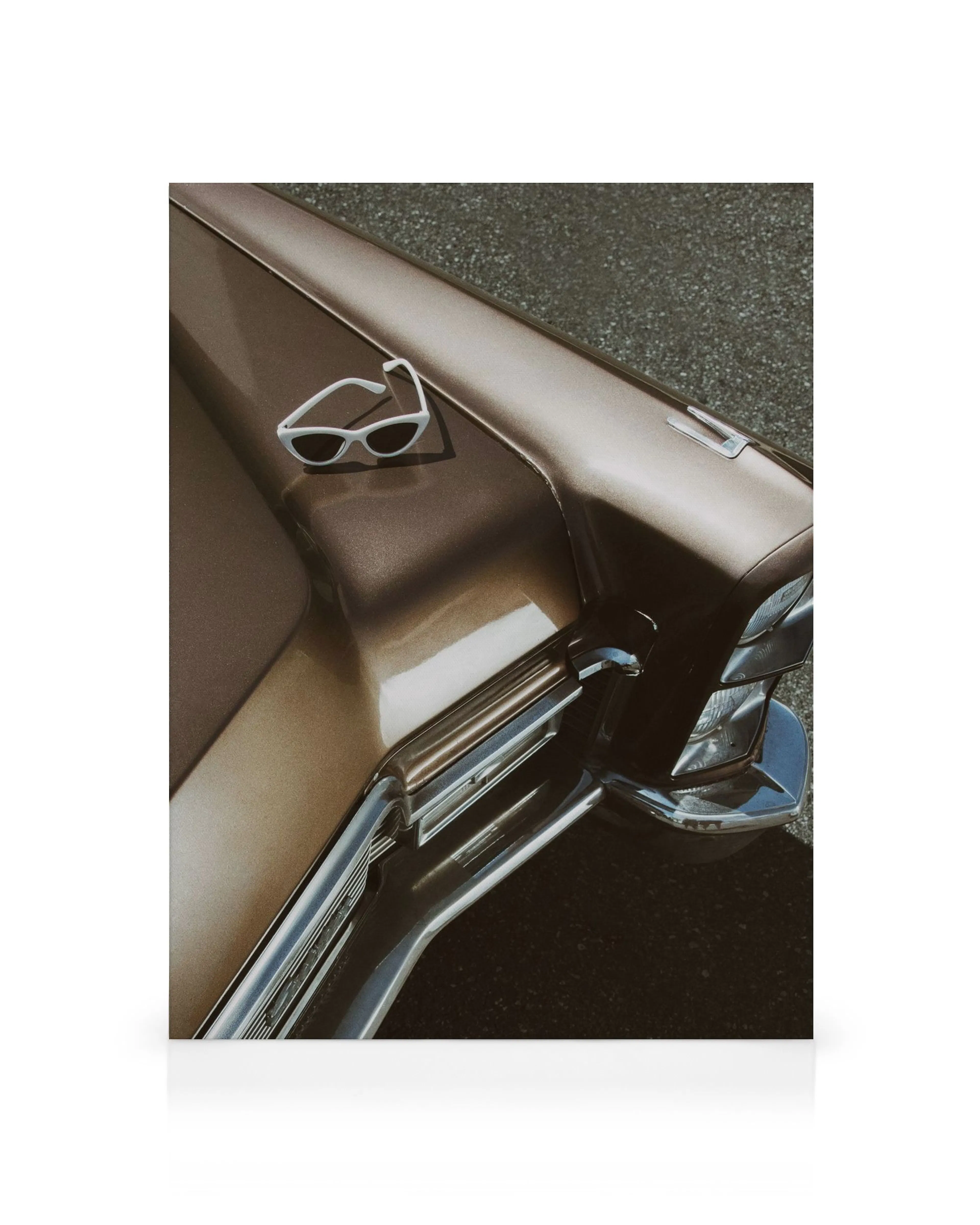 Brauner Cadillac Oldtimer mit weißer Sonnenbrille auf der Motorhaube.