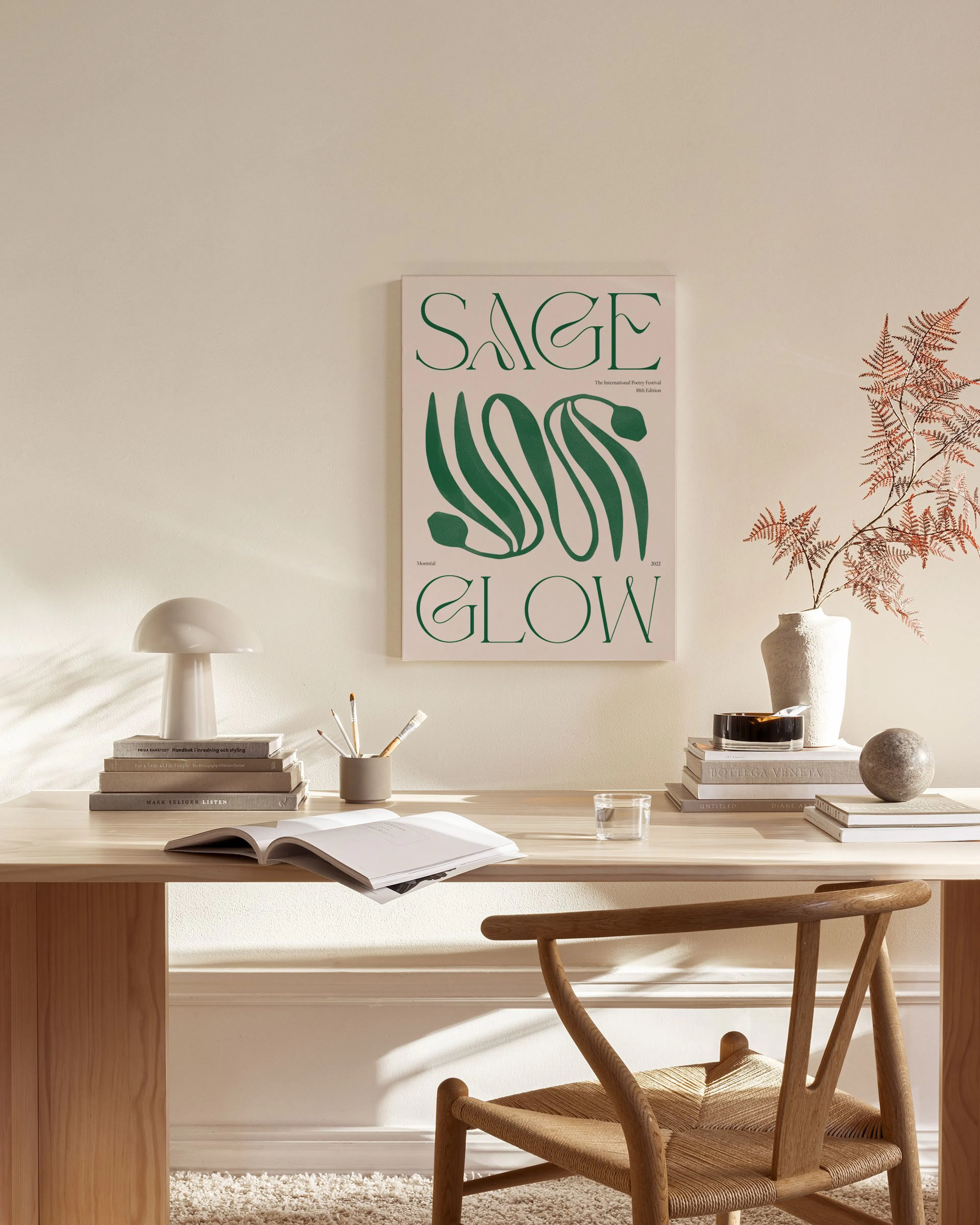 Canvastavla med grön text SAGE GLOW och organiska former på en rosa bakgrund, hängande i ett ljust vardagsrum.