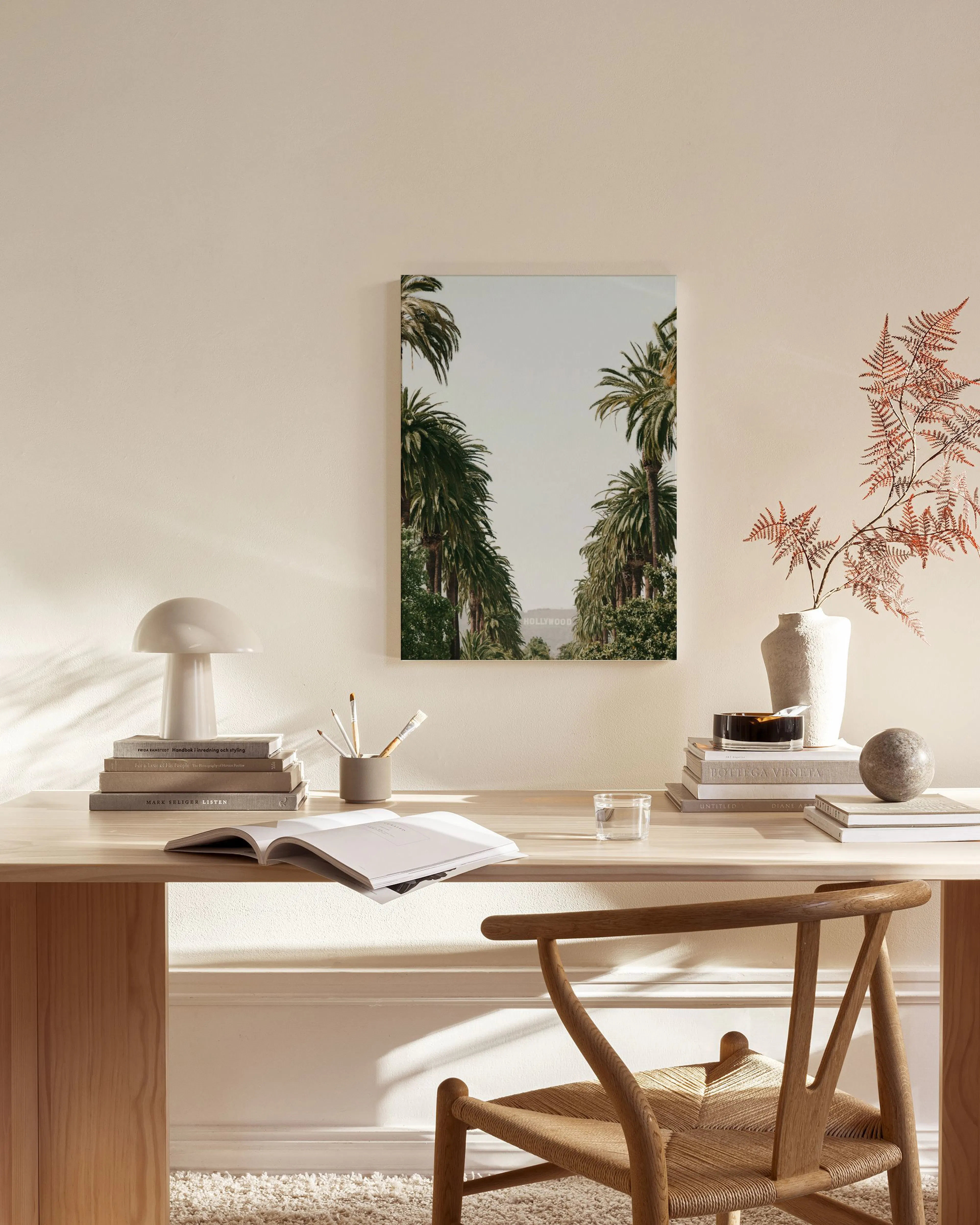 A canvas print of tall palm trees lining a street, with the Hollywood sign visible in the distance, hanging in a bright, modern 