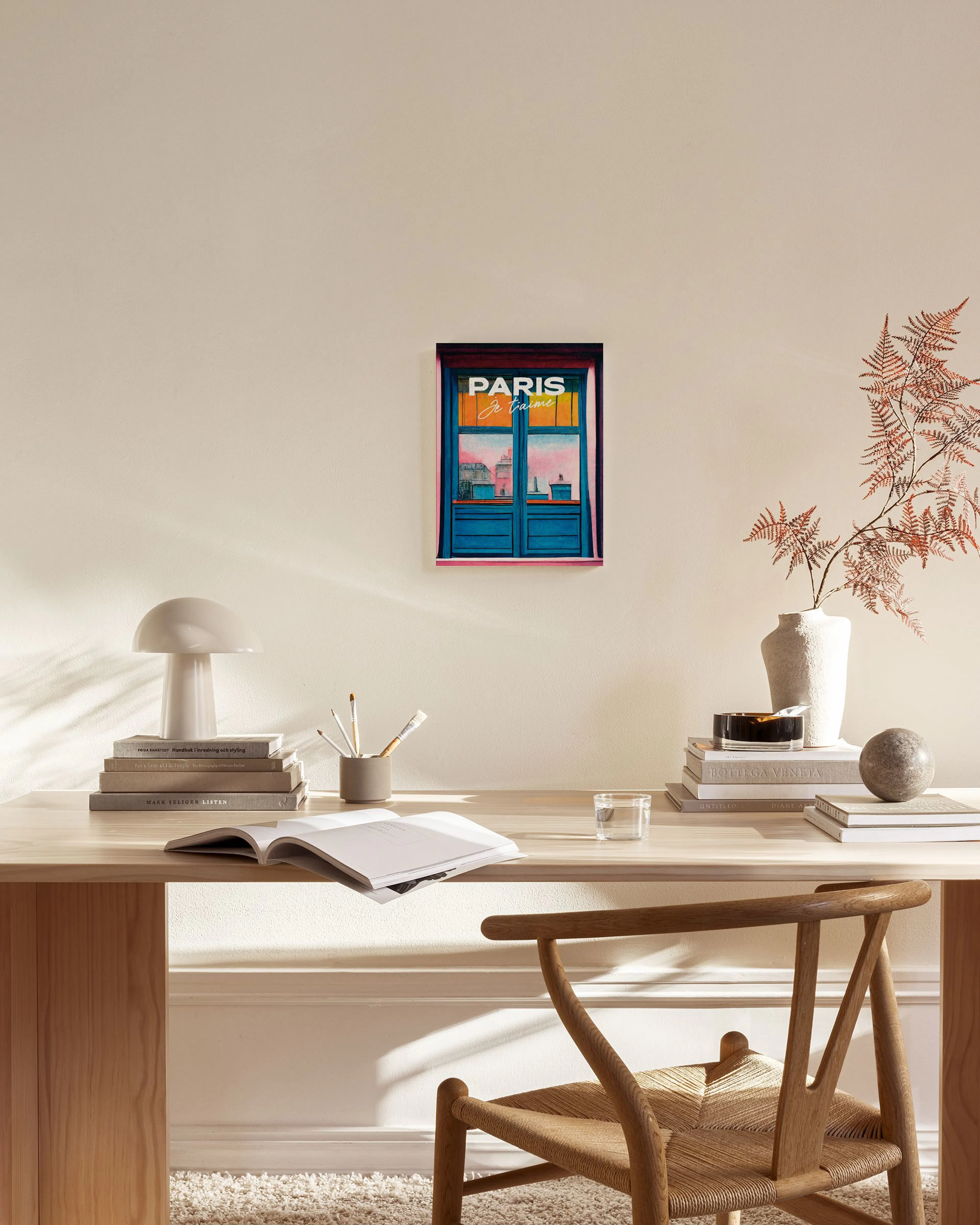 Canvastavla med en illustration av ett blått fönster, texten PARIS je taime och en rosa himmel, hängande i ett ljust vardagsrum.