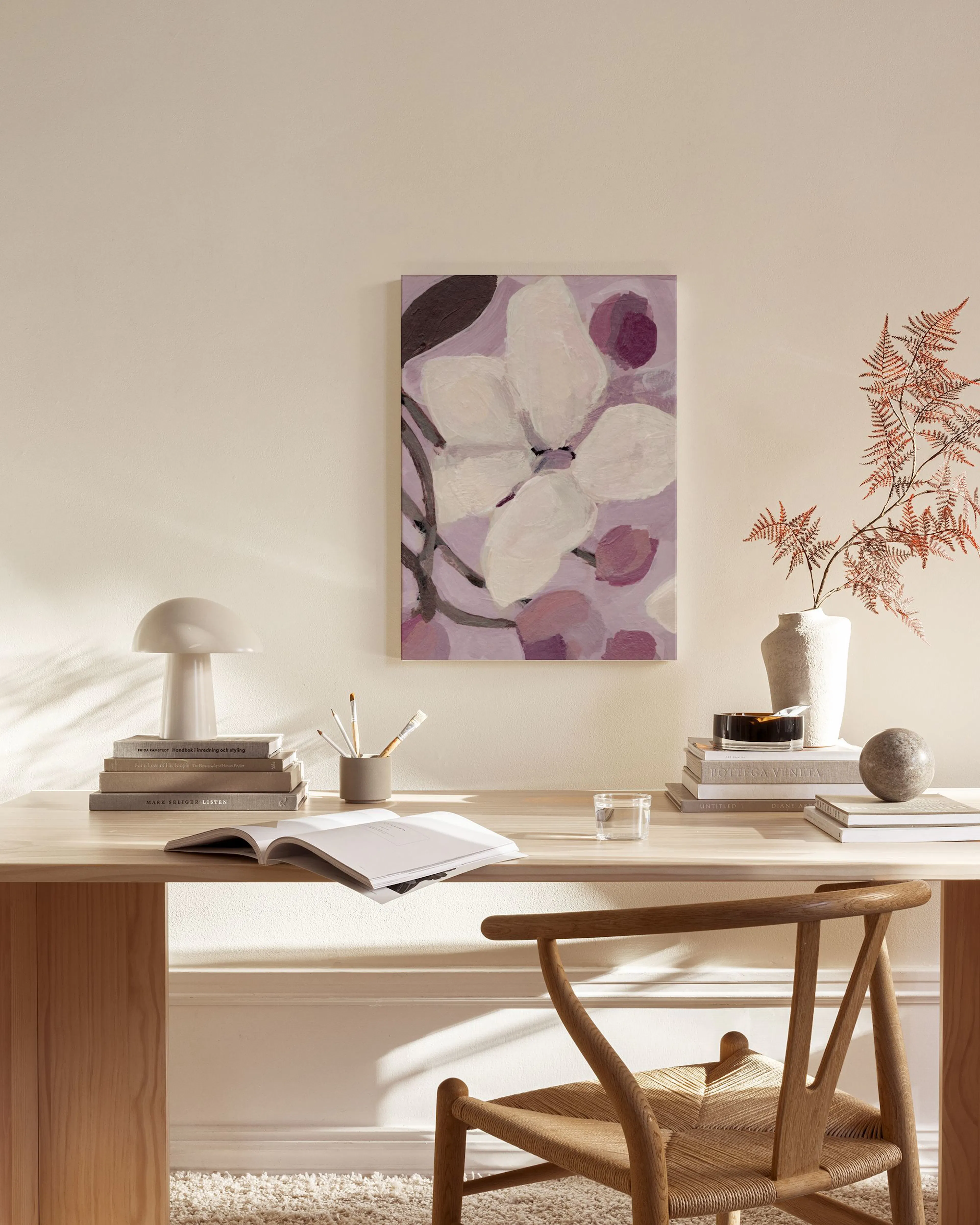 Tela decorativa com pintura abstrata de flores brancas e roxas, em tons pastel, pendurada na parede de uma sala de estar.