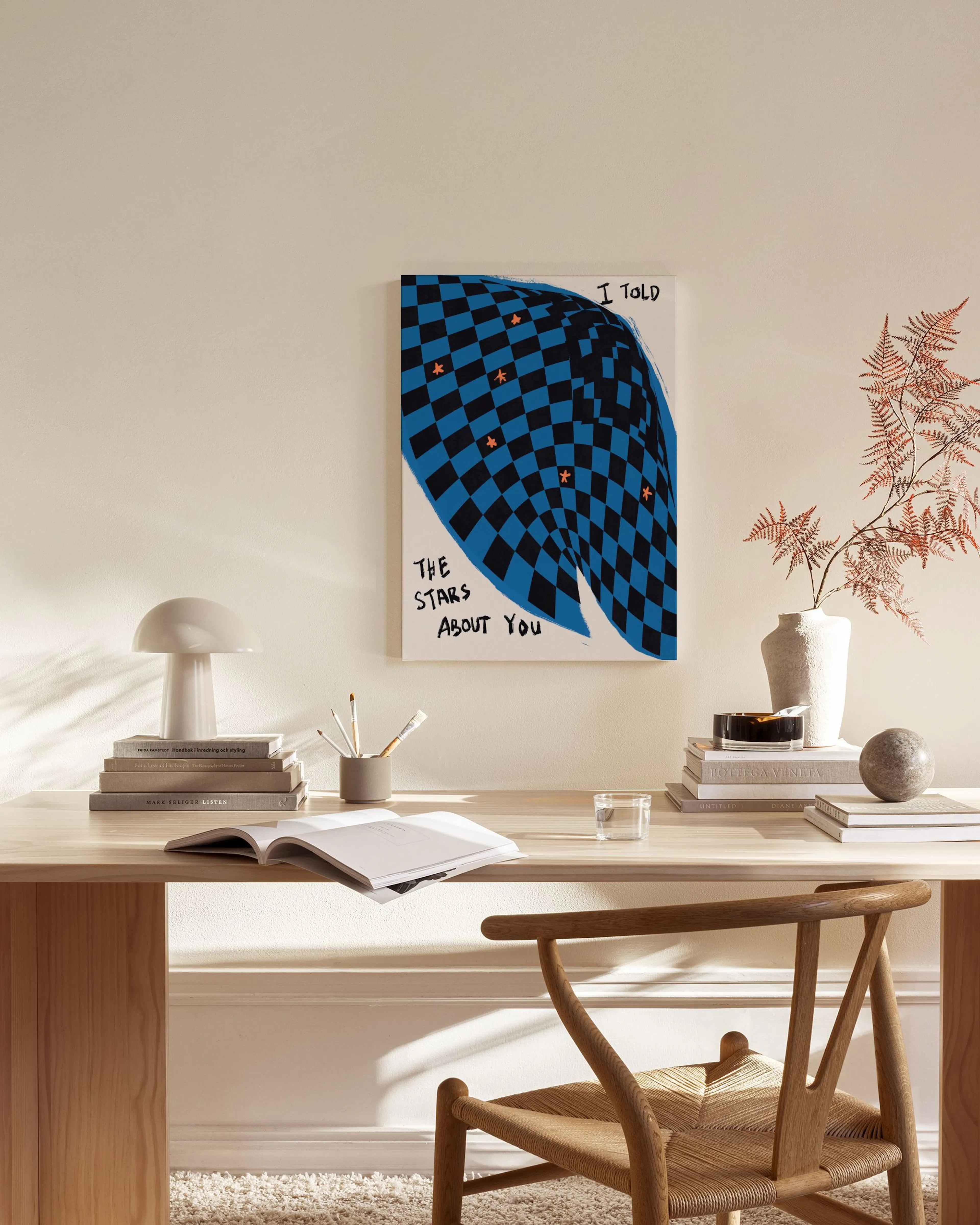 Lienzo con diseño de tablero de ajedrez azul y negro distorsionado, estrellas naranjas y texto, colgado en una sala de estar.