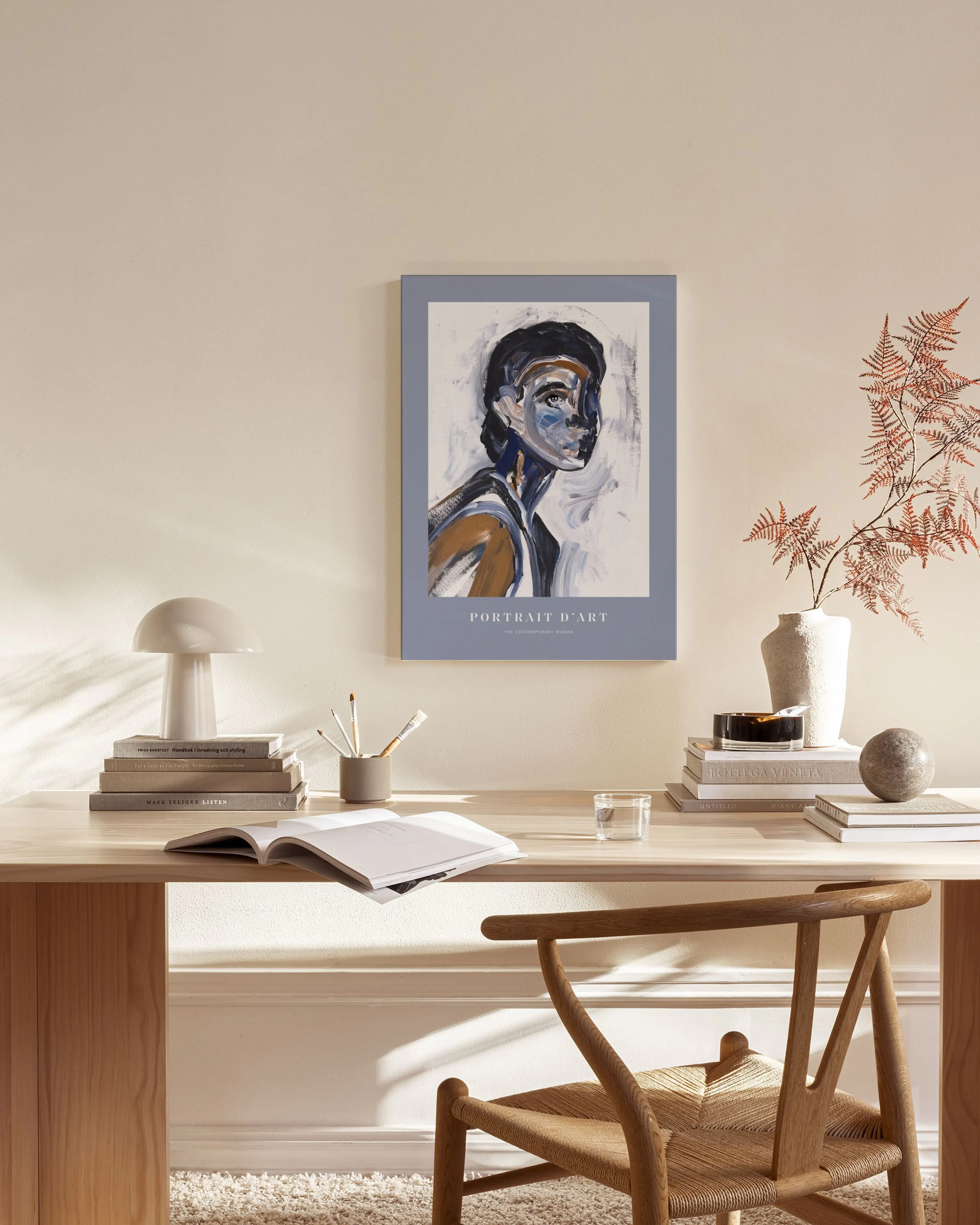 A canvas print of an abstract portrait with dark, light blue, and brown brushstrokes, hanging in a minimalist living room.