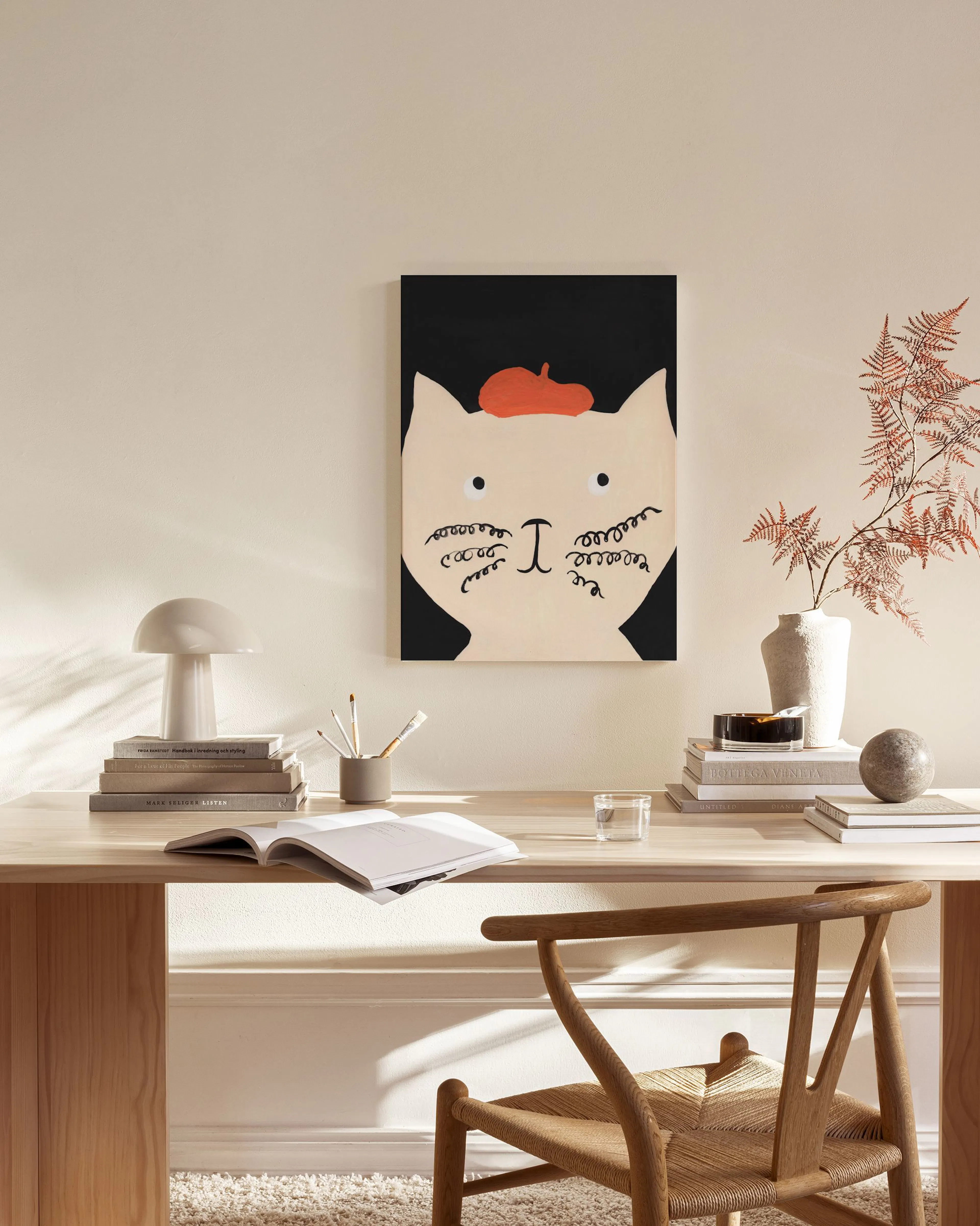 Toile dun chat blanc avec béret rouge sur fond noir, exposée dans un salon moderne.