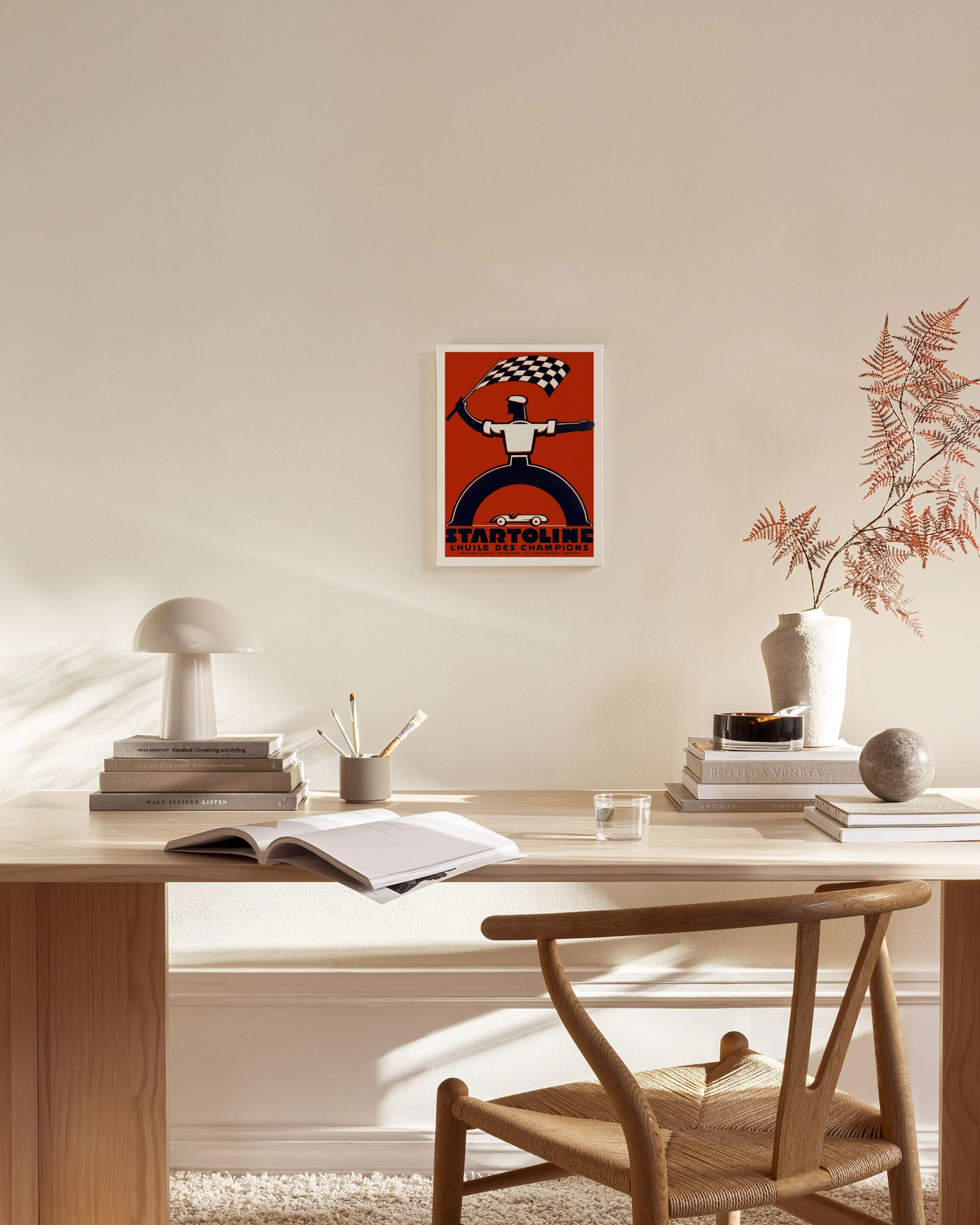 Vintage racing poster with a figure holding a checkered flag and the text STARTOLINE, hanging in a bright living room.