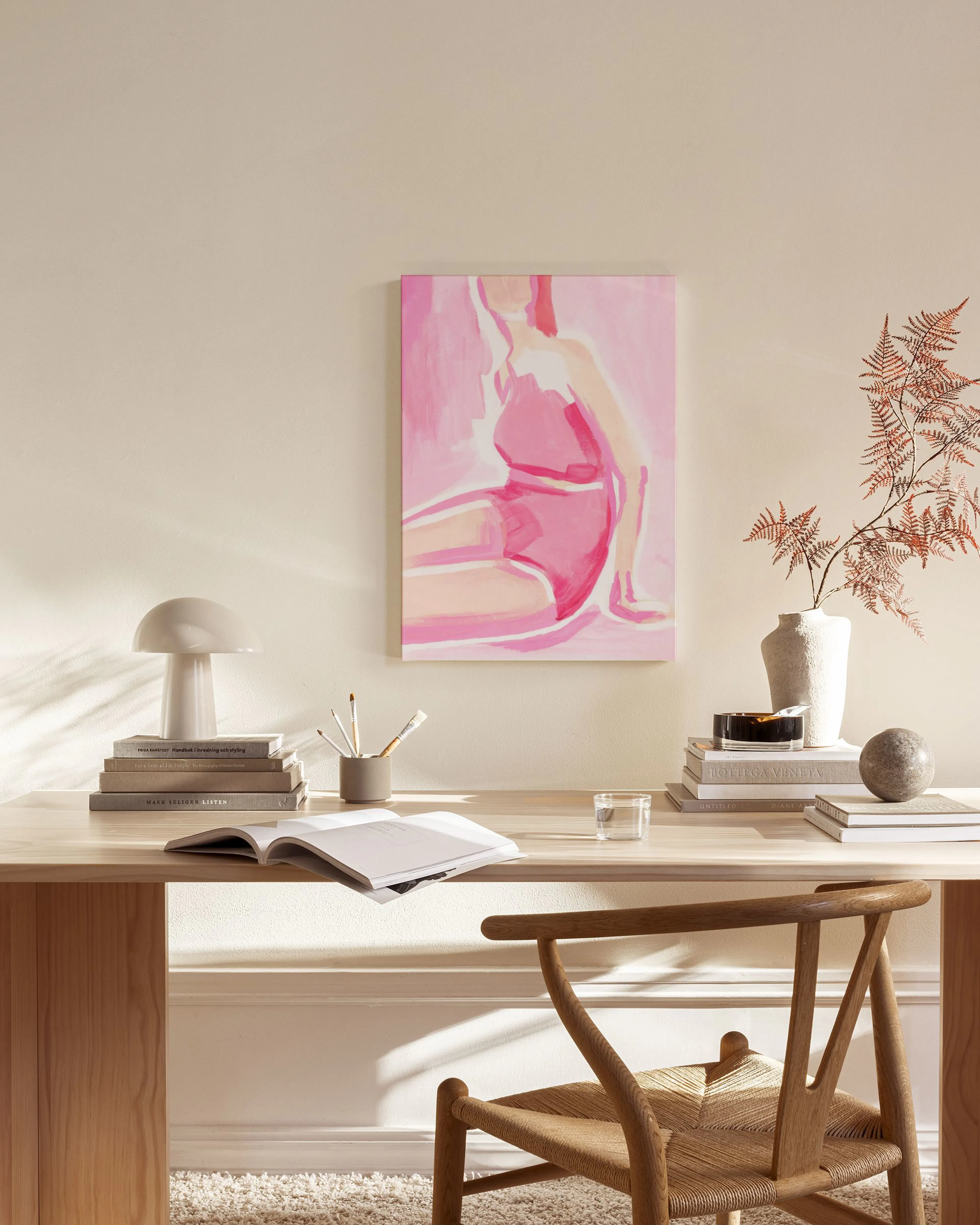 Canvastavla med en kvinna i rosa baddräkt, upphängd i ett vardagsrum ovanför en bänk och bredvid en trästol.