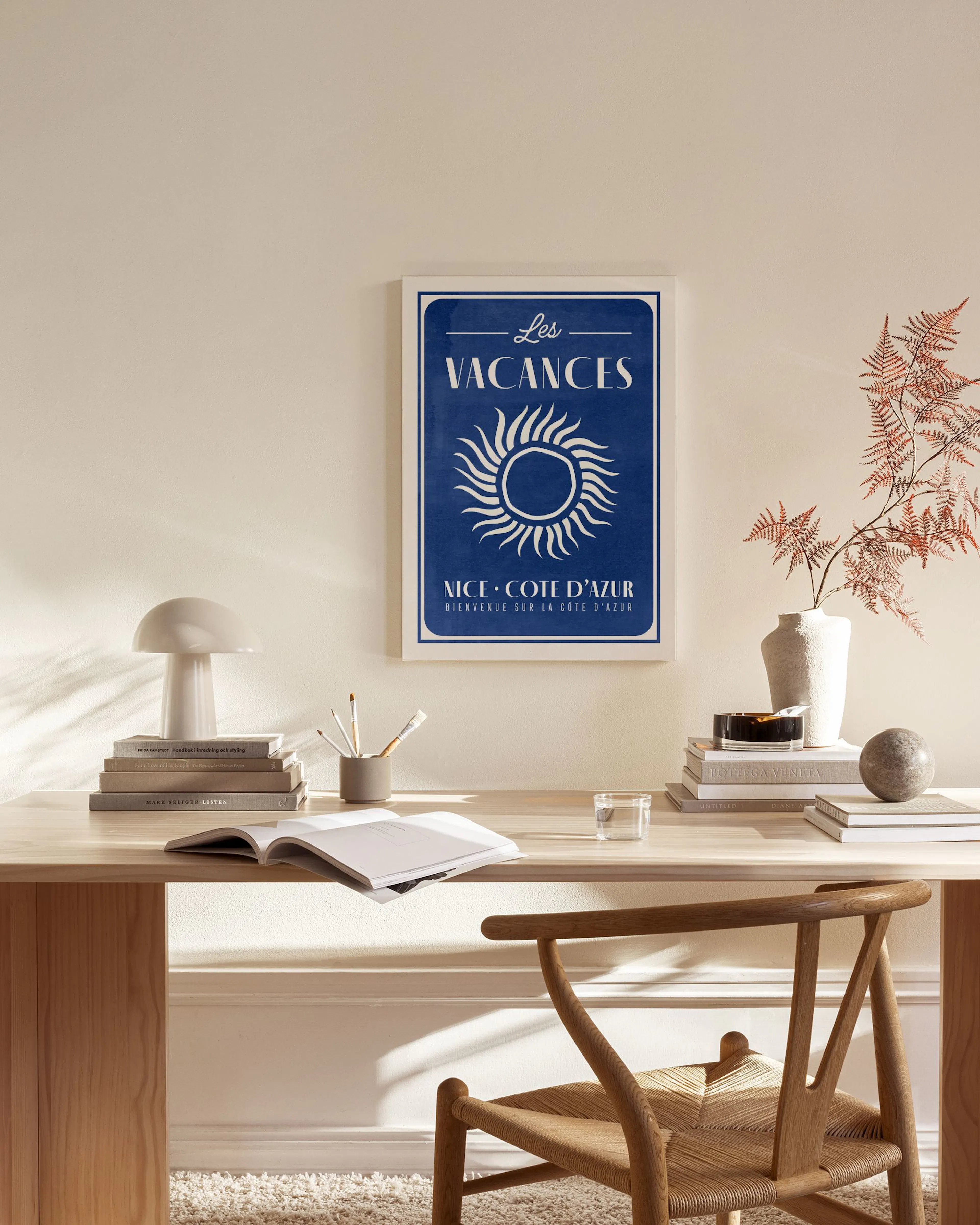 Obraz na płótnie z plakatem Les Vacances z białym słońcem na granatowym tle, wiszący w salonie nad komodą.