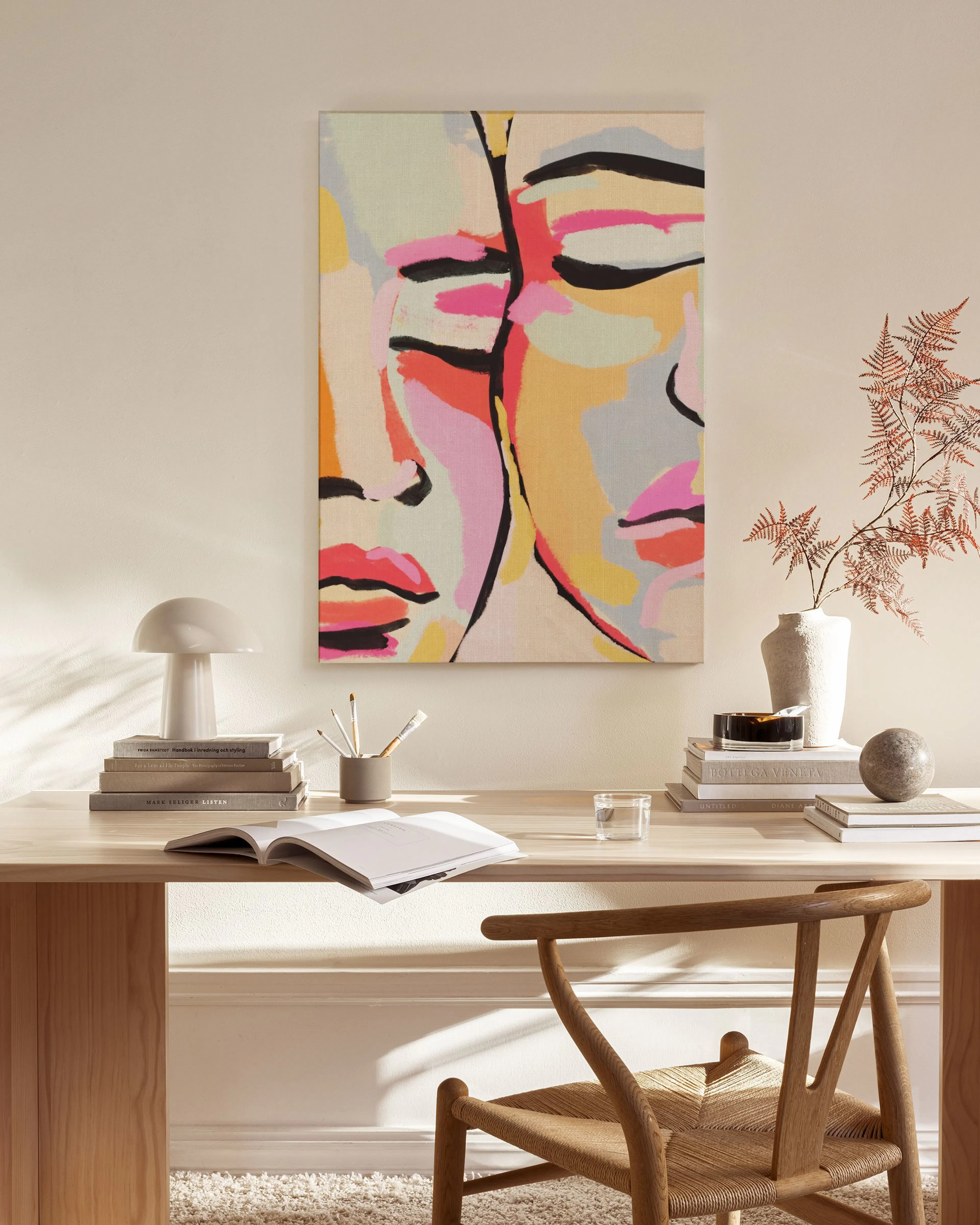 Toile murale de deux visages aux couleurs vives, rose, jaune et noir, dans un salon moderne.