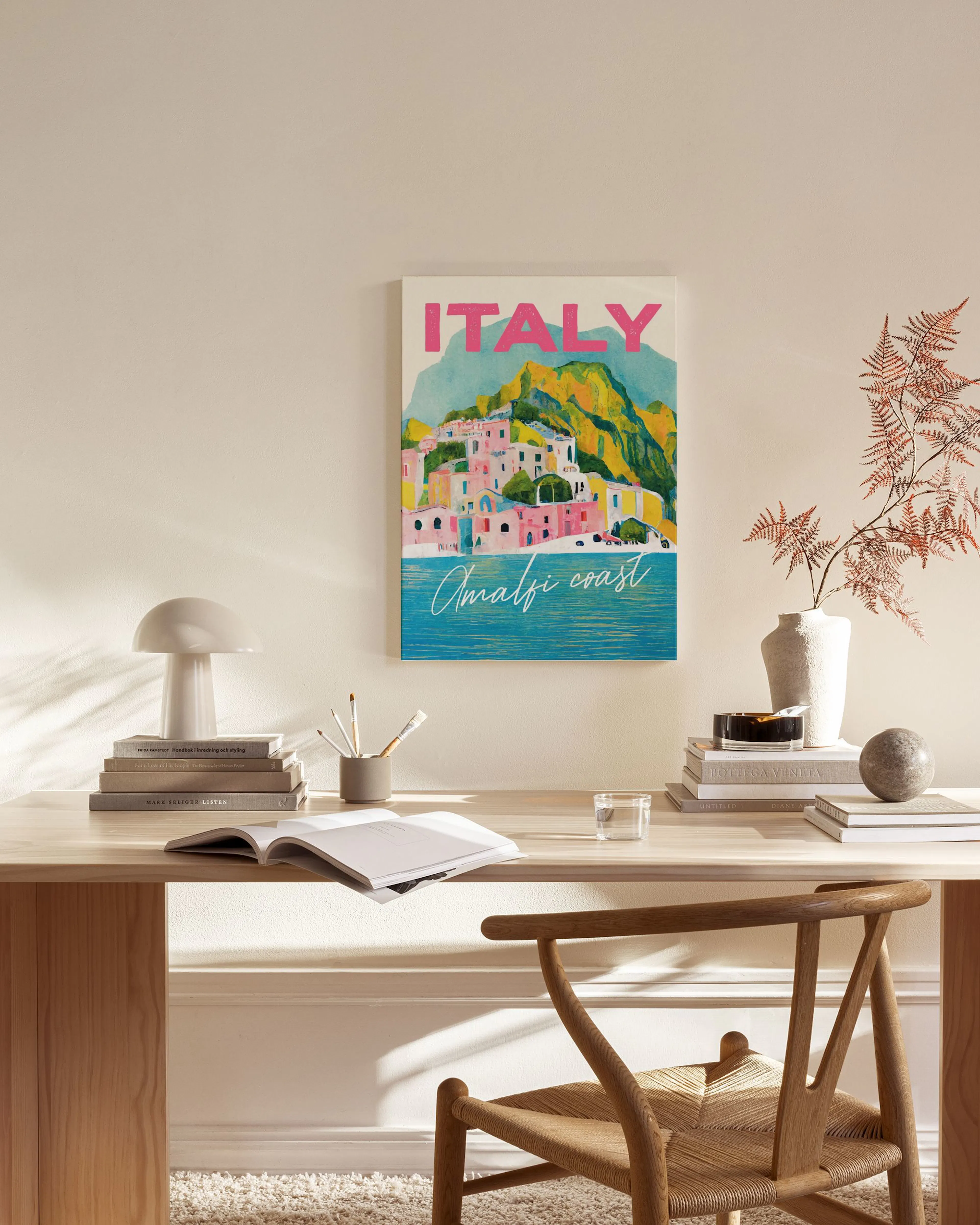 Lienzo de la costa de Amalfi con casas color pastel y montañas verdes, colgado sobre un mueble de madera en una sala de estar.