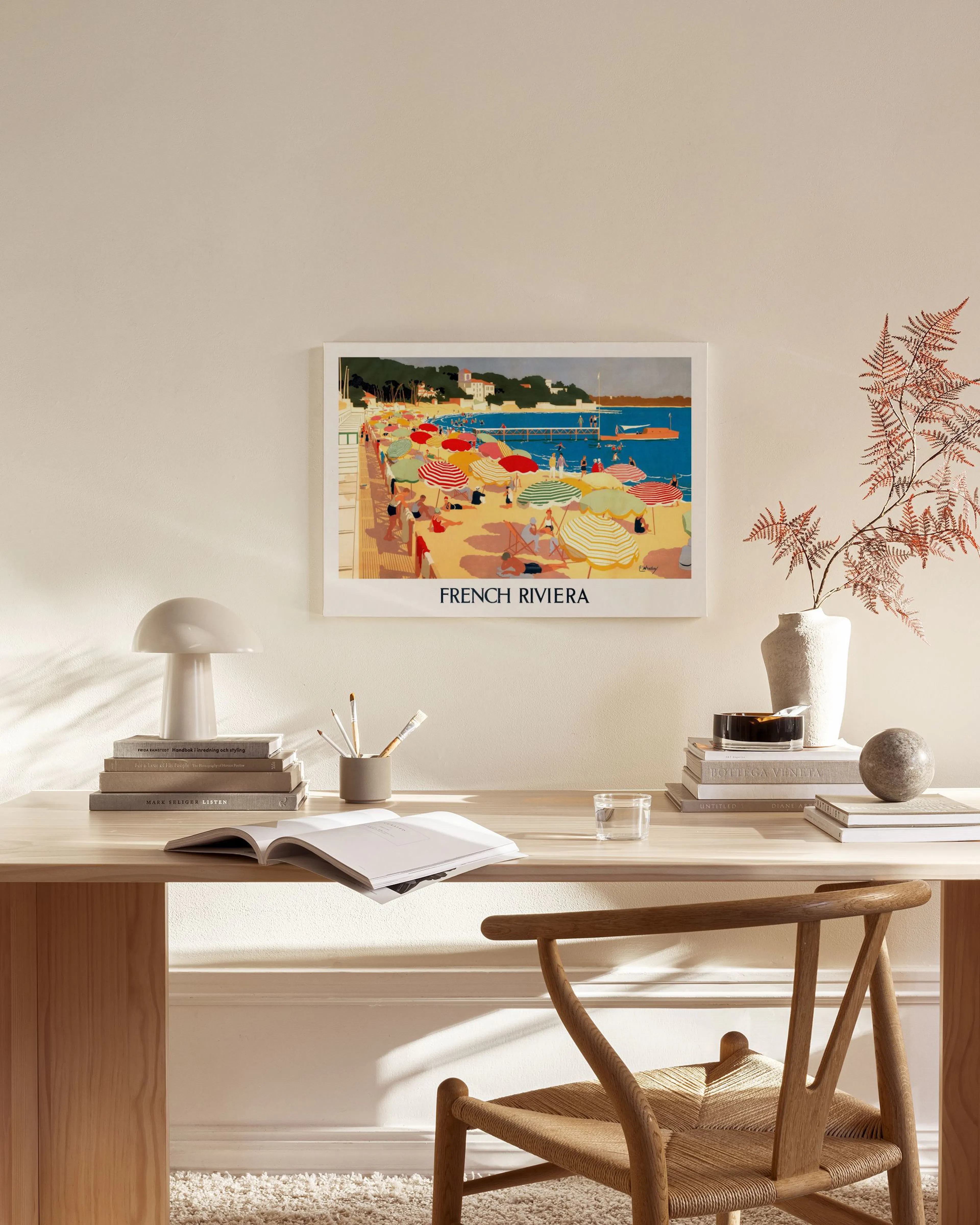 Lienzo de la Riviera Francesa con sombrillas de playa de colores, colgado en una sala de estar de tonos neutros.