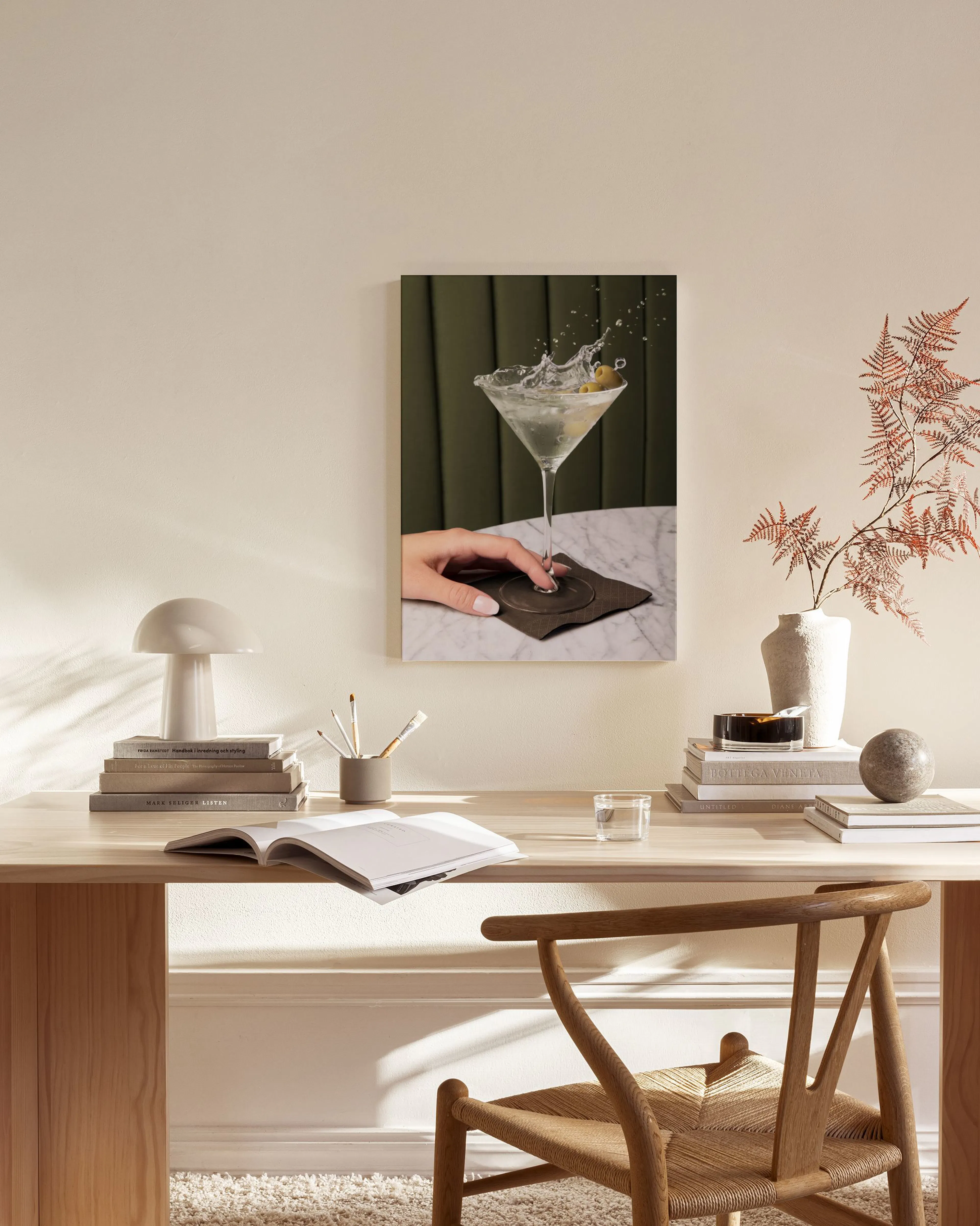 Leinwandbild eines spritzenden Martinis mit Olive und Hand, hängt im modernen Wohnzimmer über einem Sideboard.