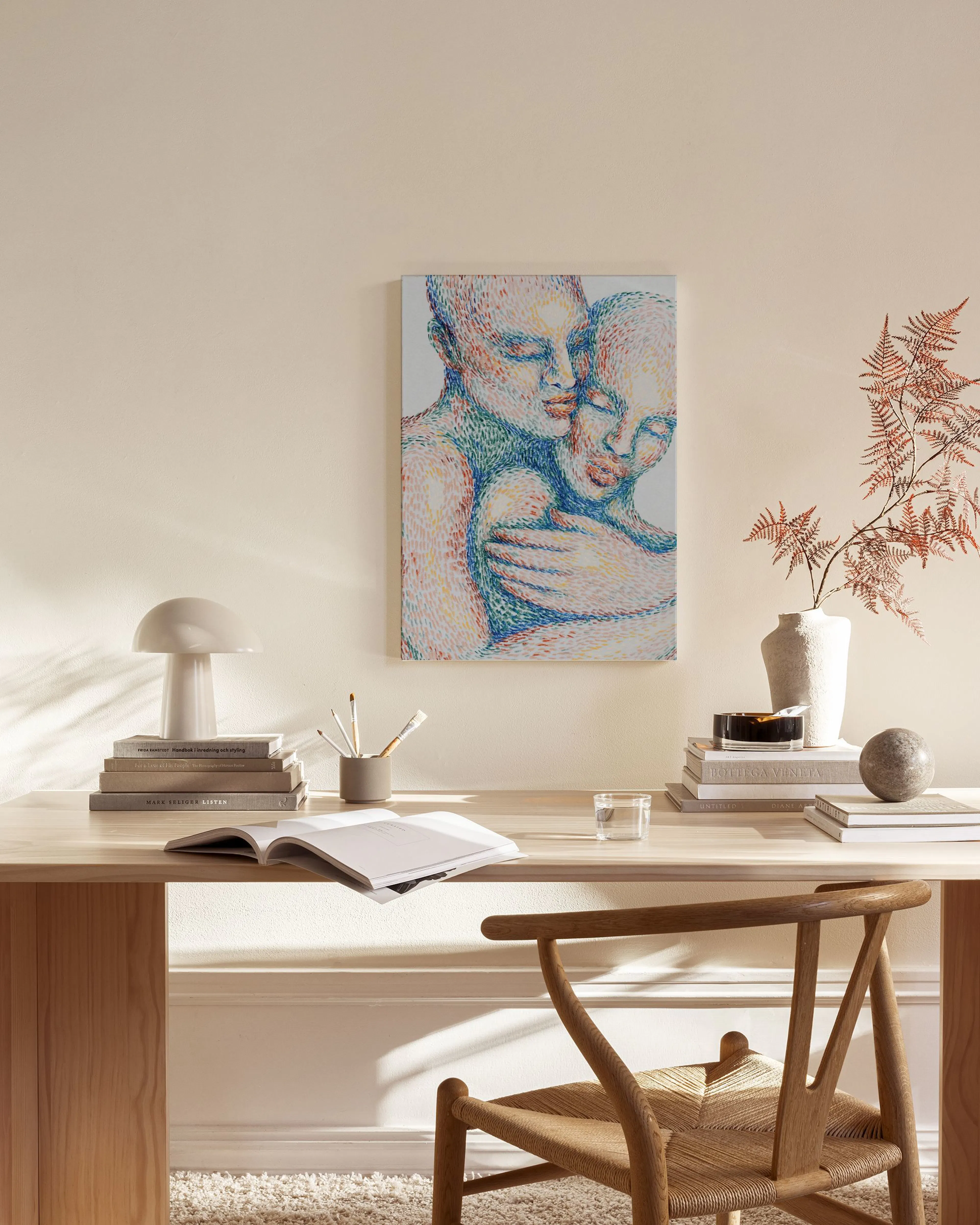 A colorful pointillist-style canvas print of two embracing figures, displayed above a wooden console table in a minimalist livin