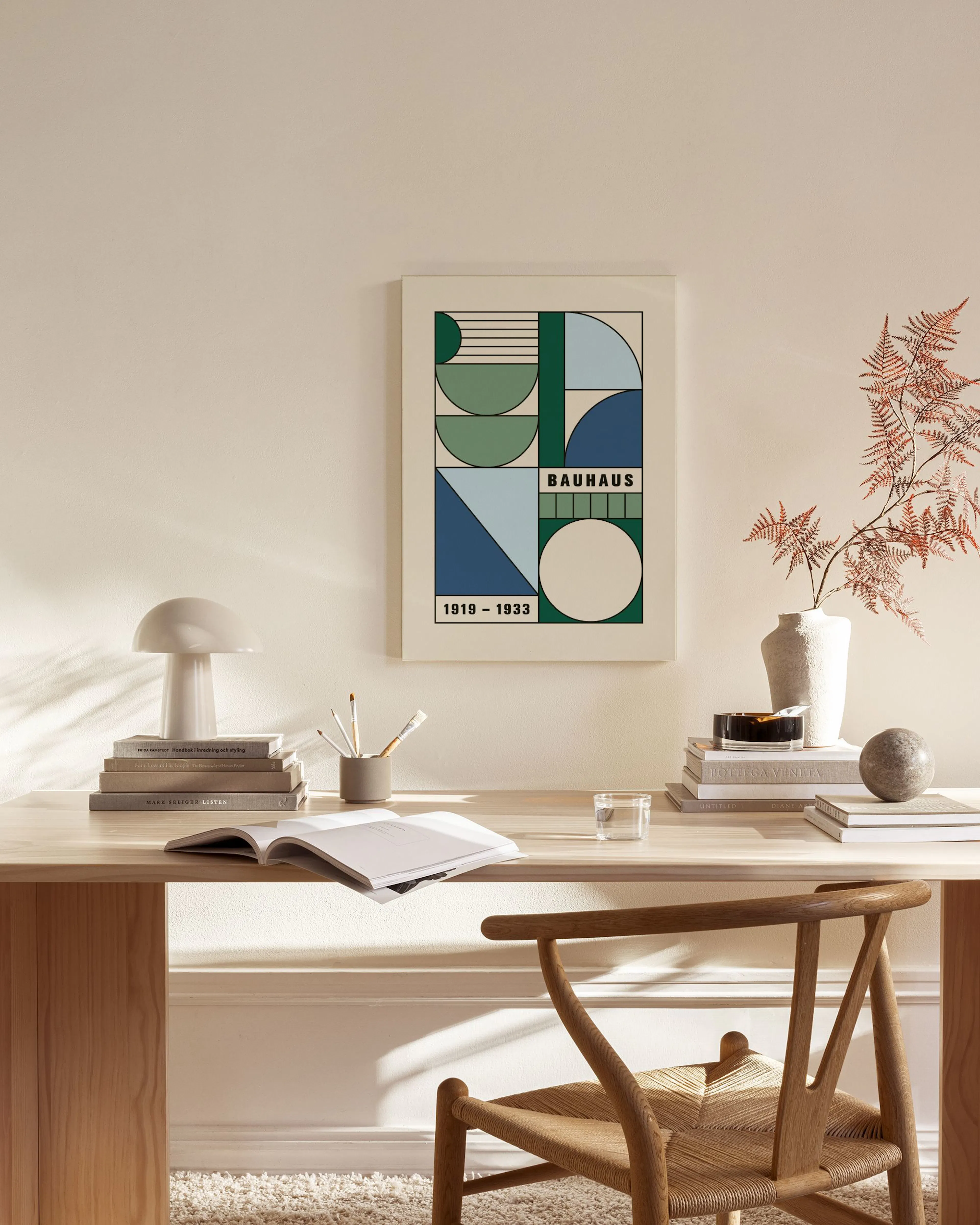 Lærred med geometrisk Bauhaus-design i grønne, blå og beige nuancer, ophængt i en lys stue.