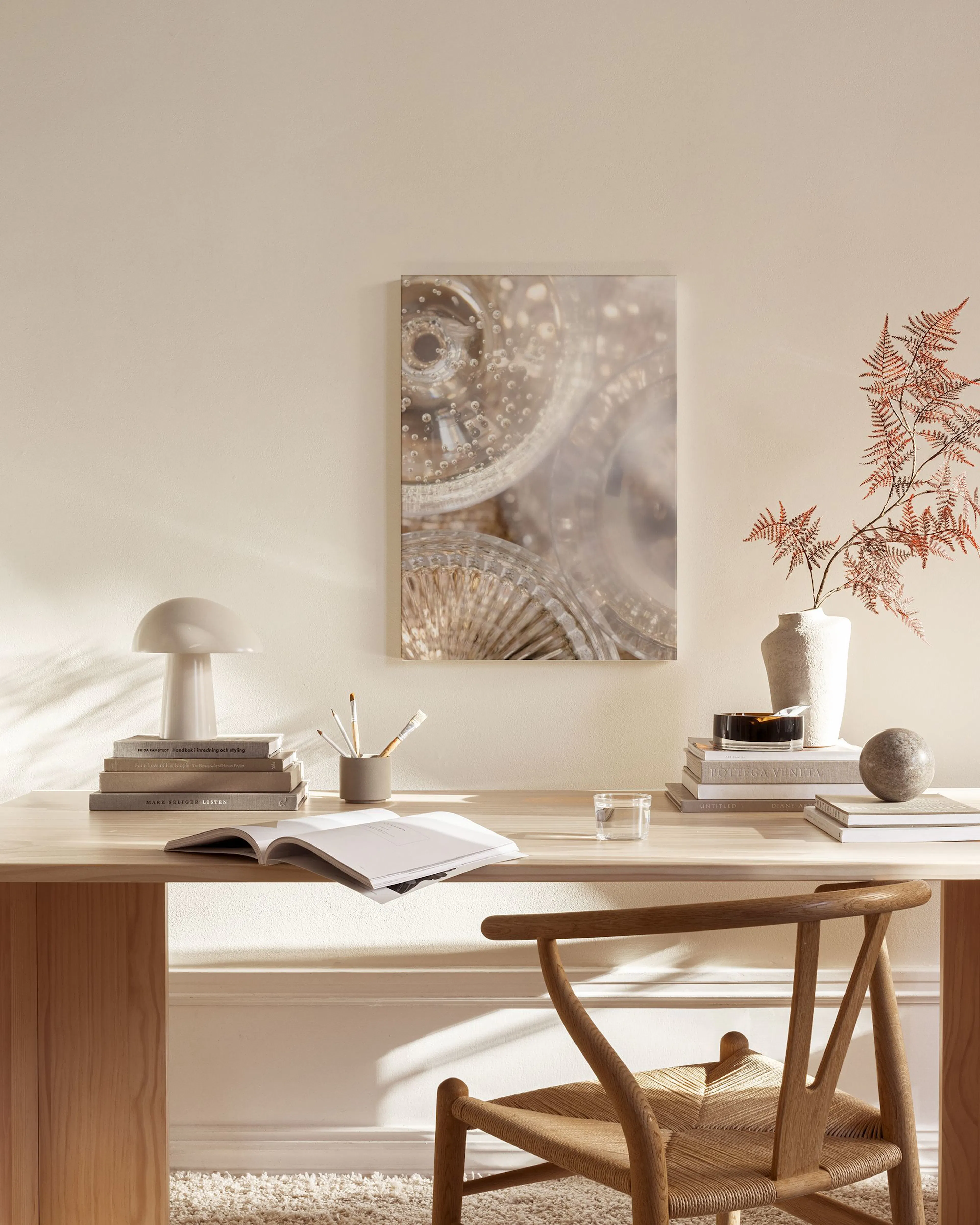 A canvas print displaying abstract glass shapes with bubbles, hanging in a bright, minimalist living room above a wooden console