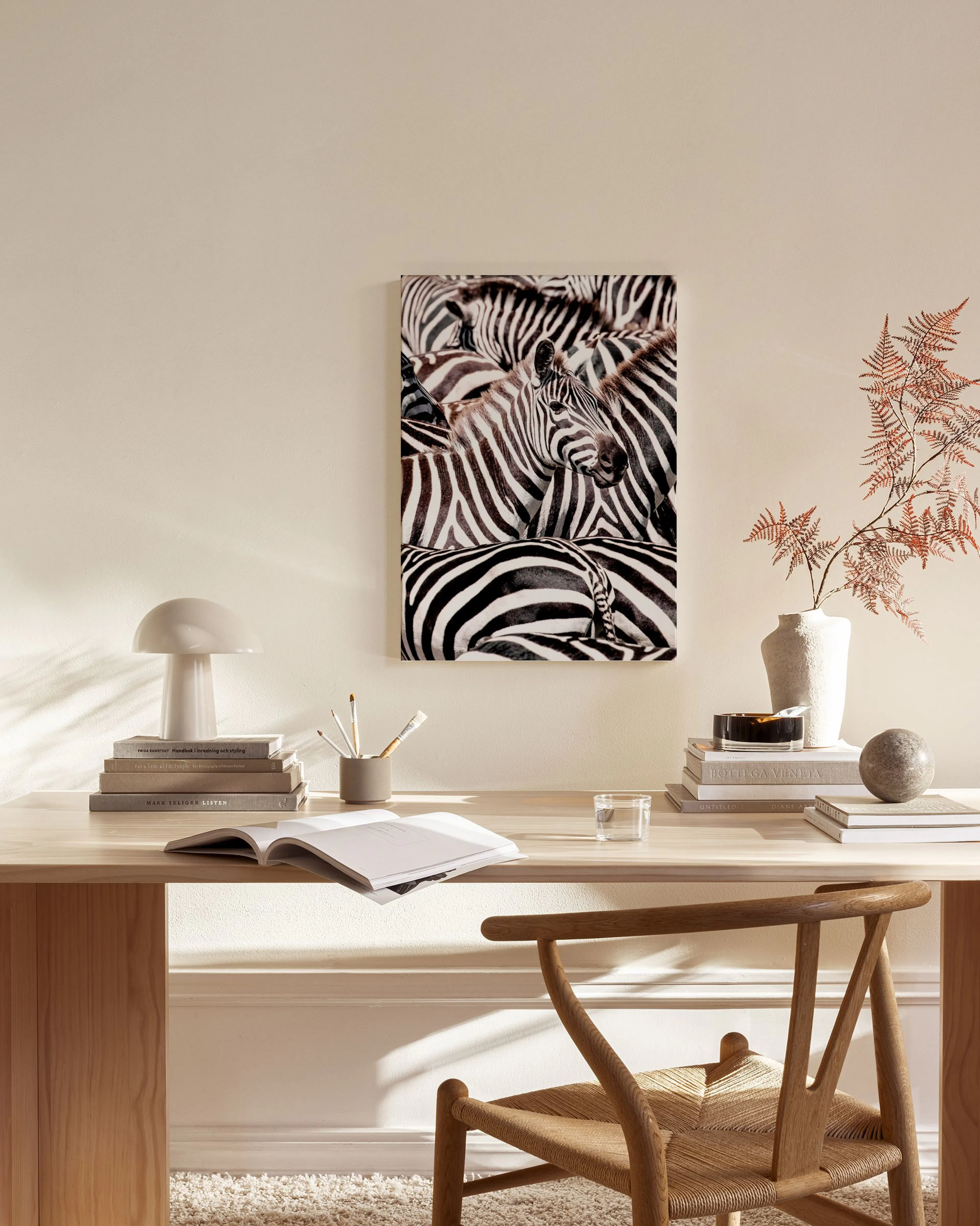 Toile zèbres noir et blanc en gros plan, accrochée au mur clair dun salon moderne avec fauteuil en bois.