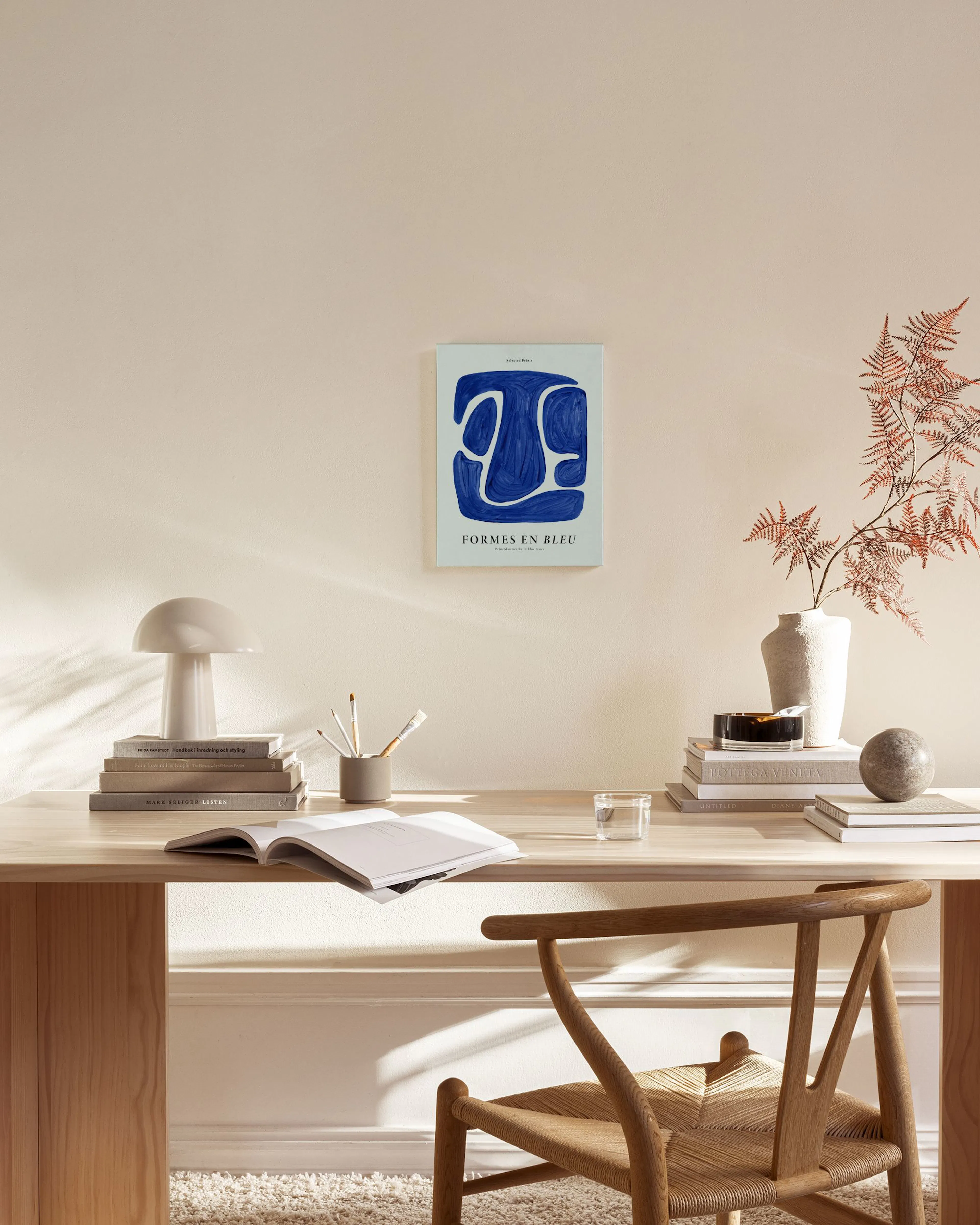 Tela decorativa Formes en Bleu com formas abstratas azuis e linhas brancas, exposta numa sala de estar minimalista com mobiliári