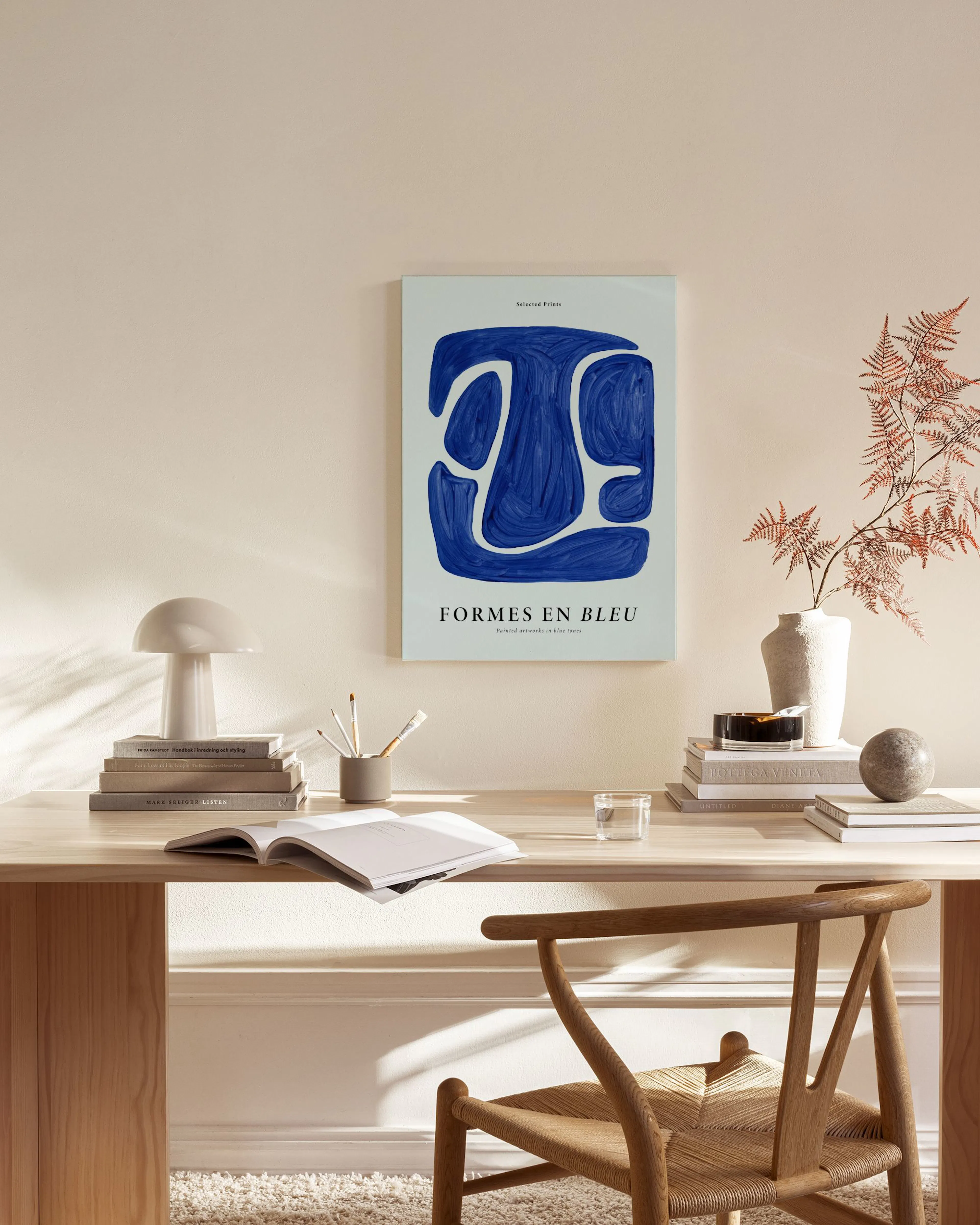 A canvas print with blue abstract shapes on a light blue background, hanging above a wooden console table in a minimalist living