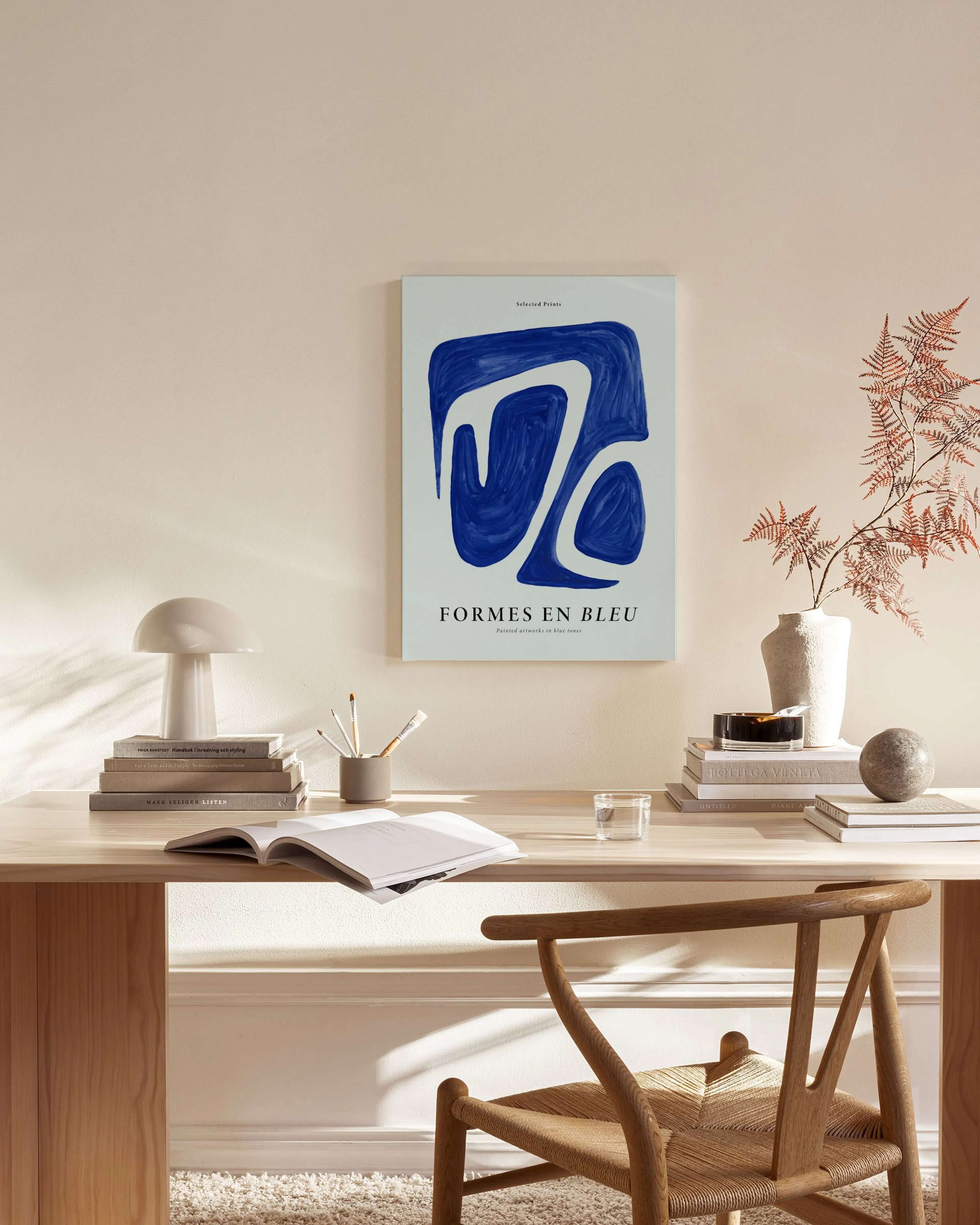 A blue abstract print with white organic shapes, titled FORMES EN BLEU, hanging in a modern living room above a wooden console.