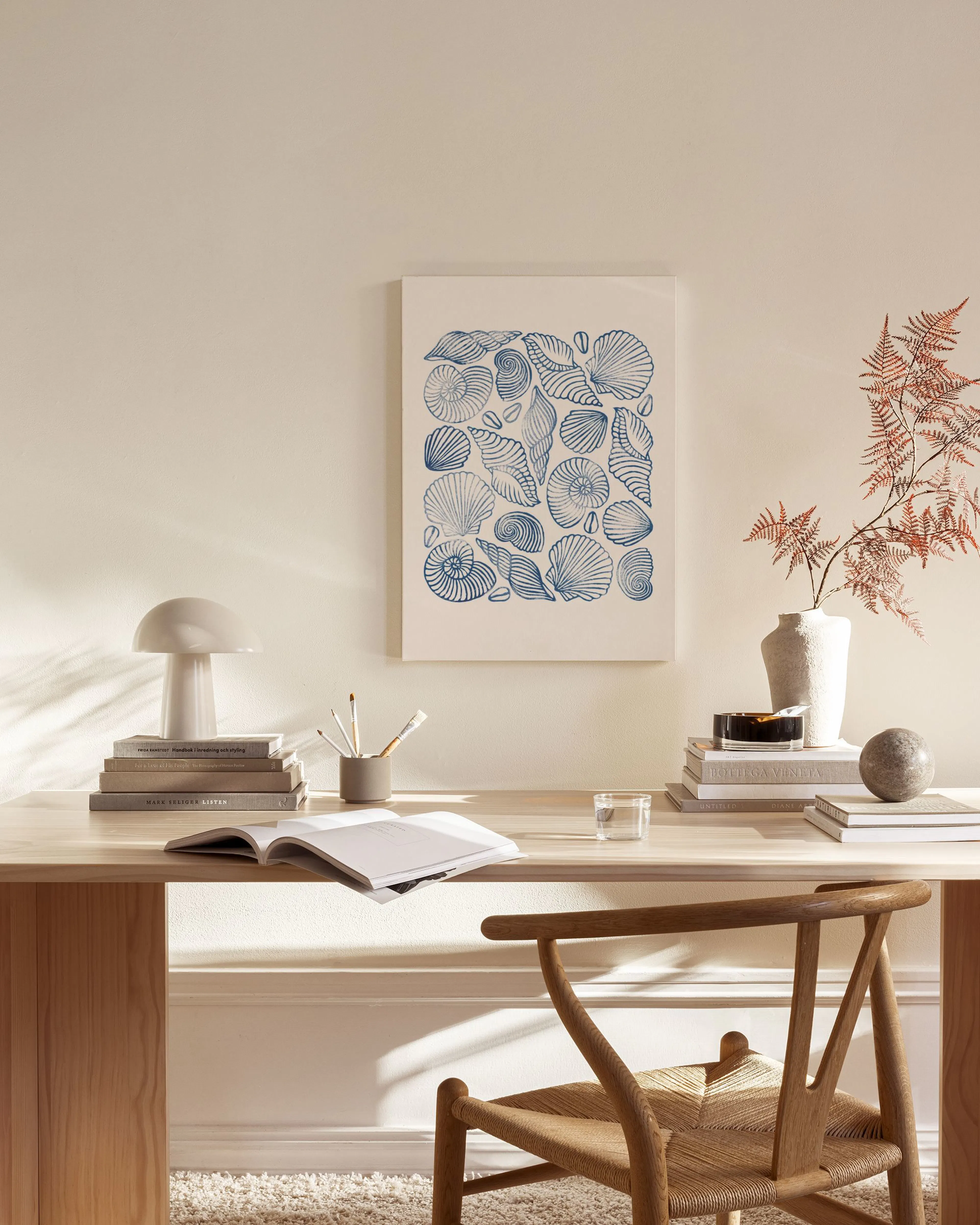 Leinwandbild mit blauen Muscheln auf hellem Hintergrund, im modernen Wohnzimmer über einem Sideboard.