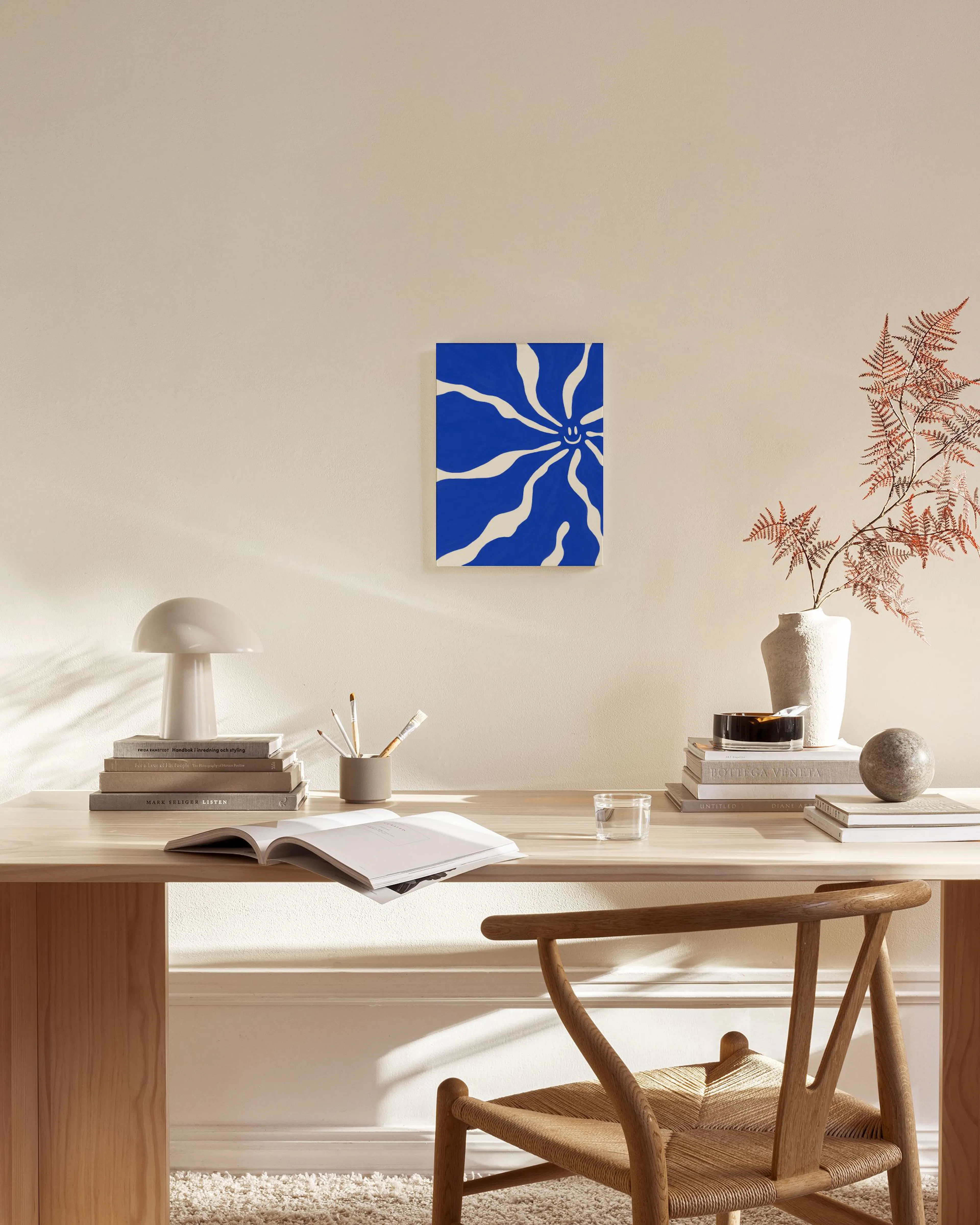 Leinwandbild mit blauem Smiley-Motiv und weißen Wellen, hängt über einem Holzregal im Wohnzimmer.