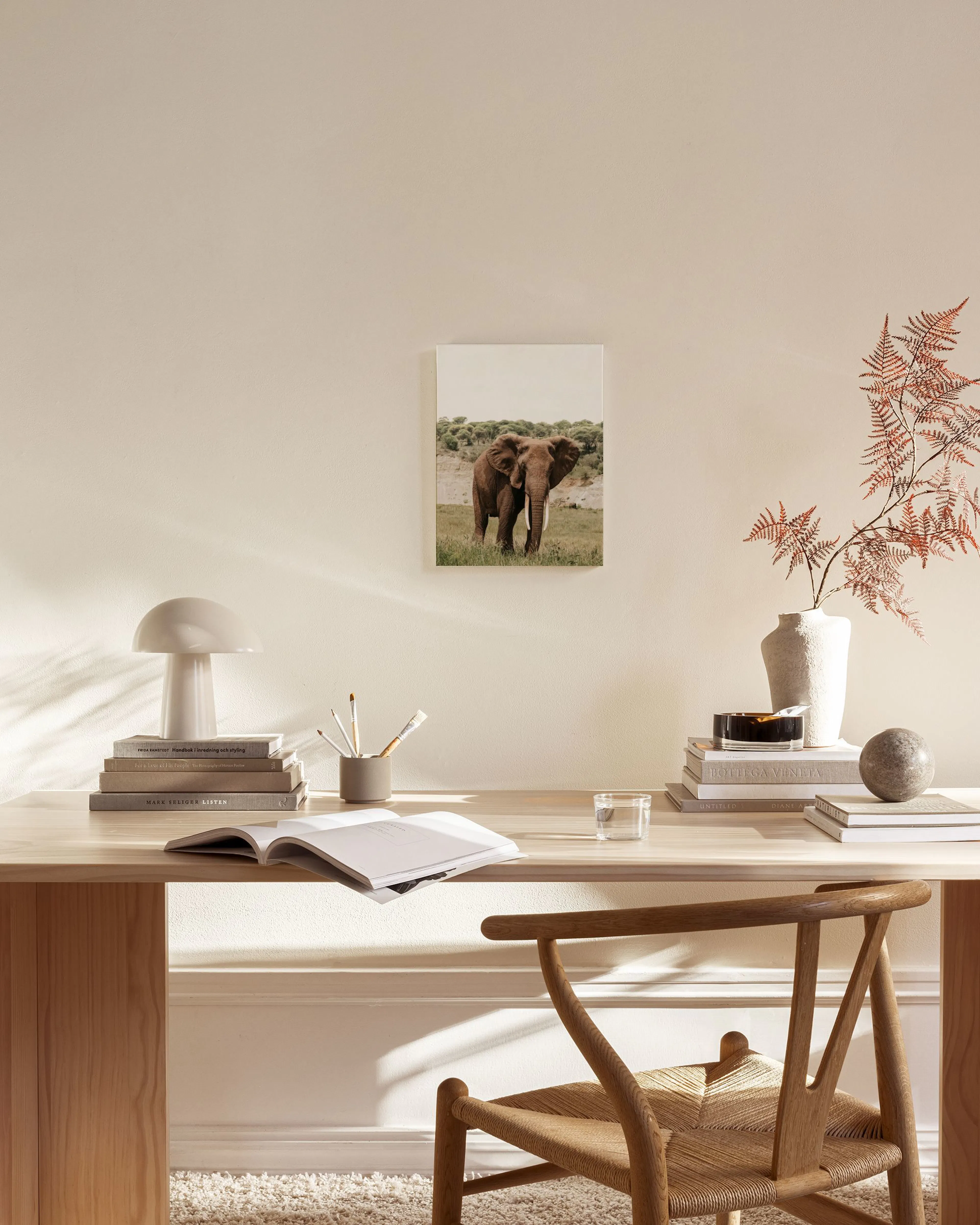 Canvas met olifant in Afrikaans landschap, hangend boven een houten dressoir in een lichte woonkamer.