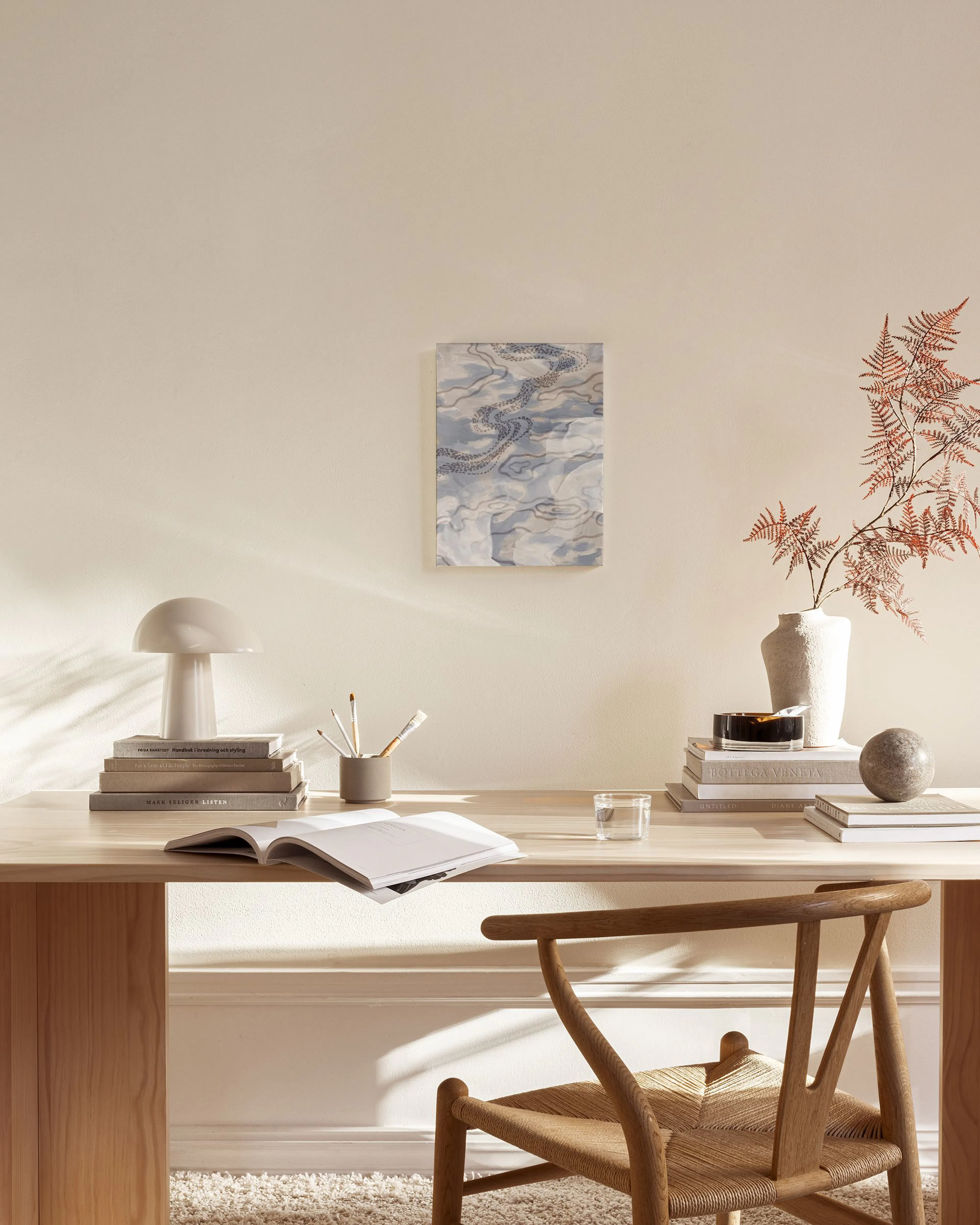 Canvas met blauwgrijze golvende lijnen en beige organische vormen, hangend boven een houten dressoir in een woonkamer.
