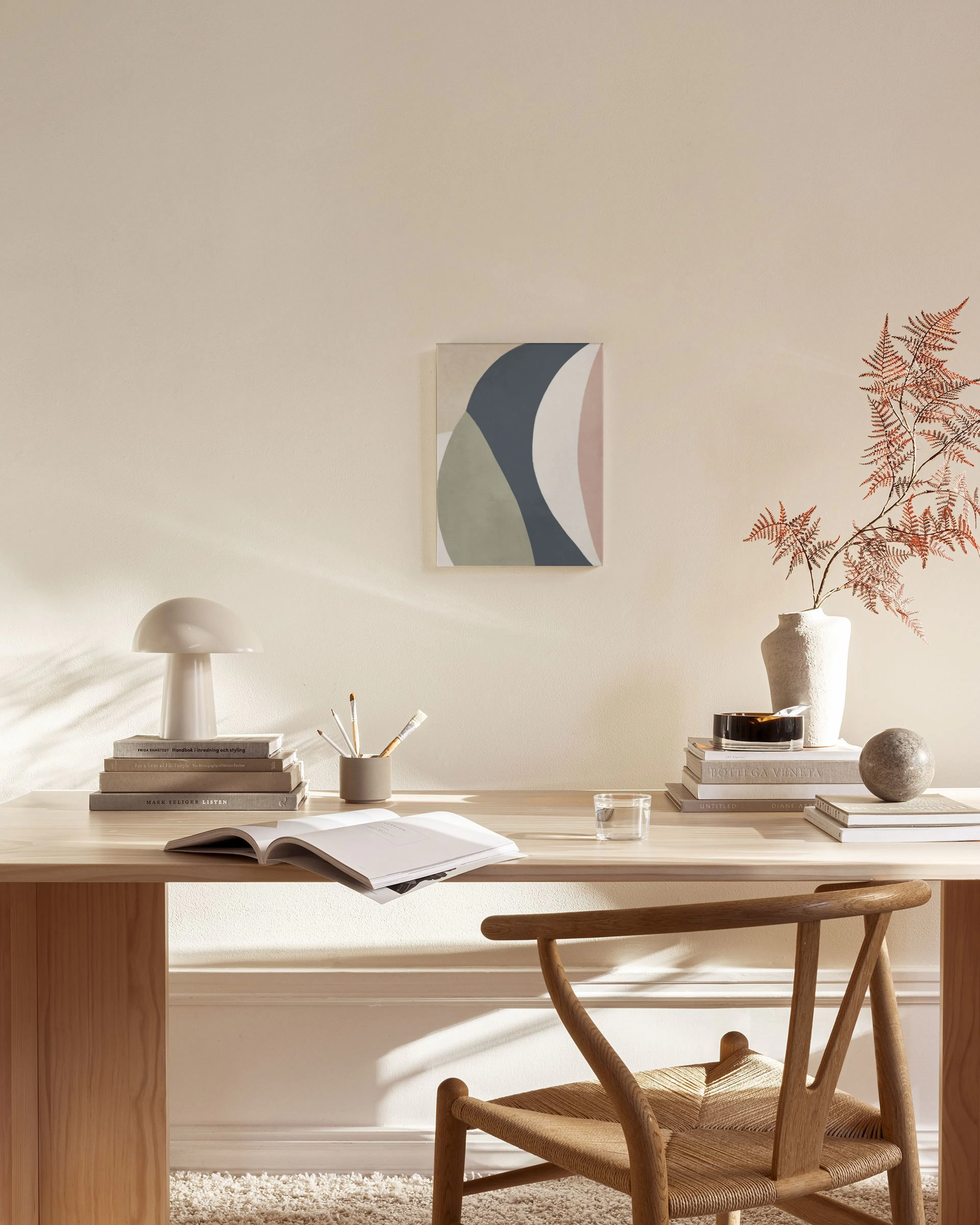 Abstract canvas print with organic shapes in blue, green, white, and pink, hanging above a console table in a living room.