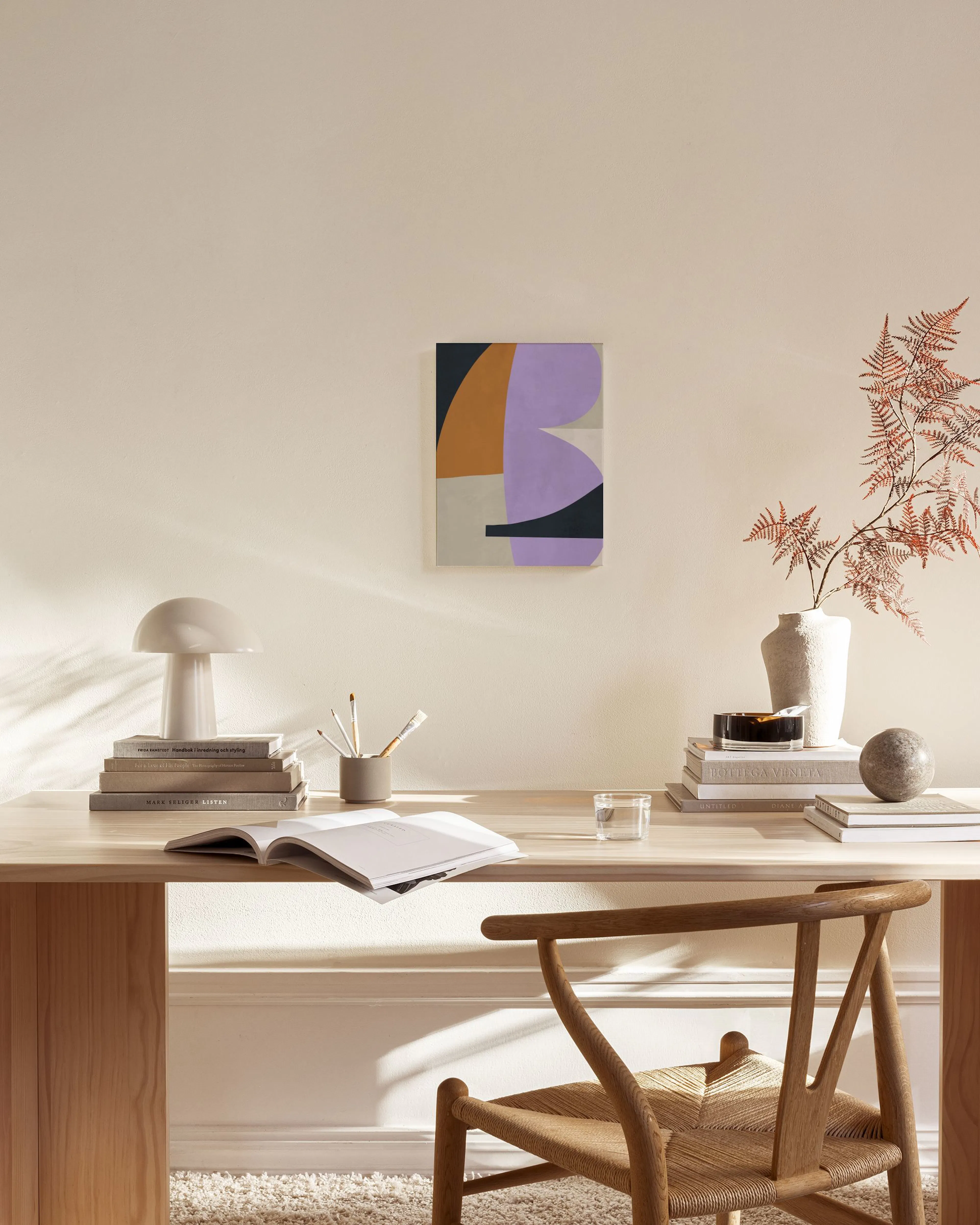Geometric abstract canvas print with purple, orange, black, and beige shapes, displayed in a bright living room.