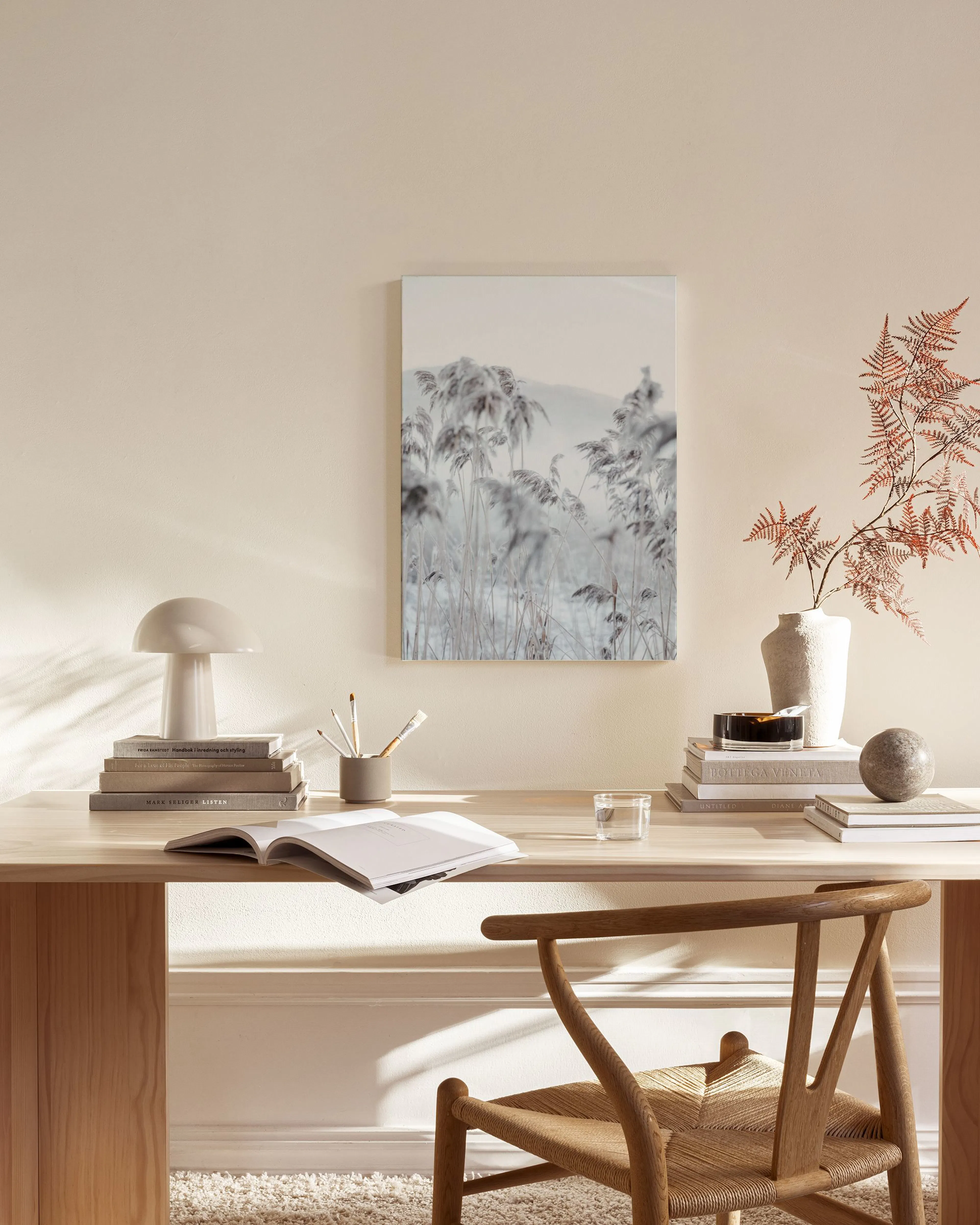 Toile murale de plantes givrées aux tons gris et blancs, suspendue dans un salon beige épuré.
