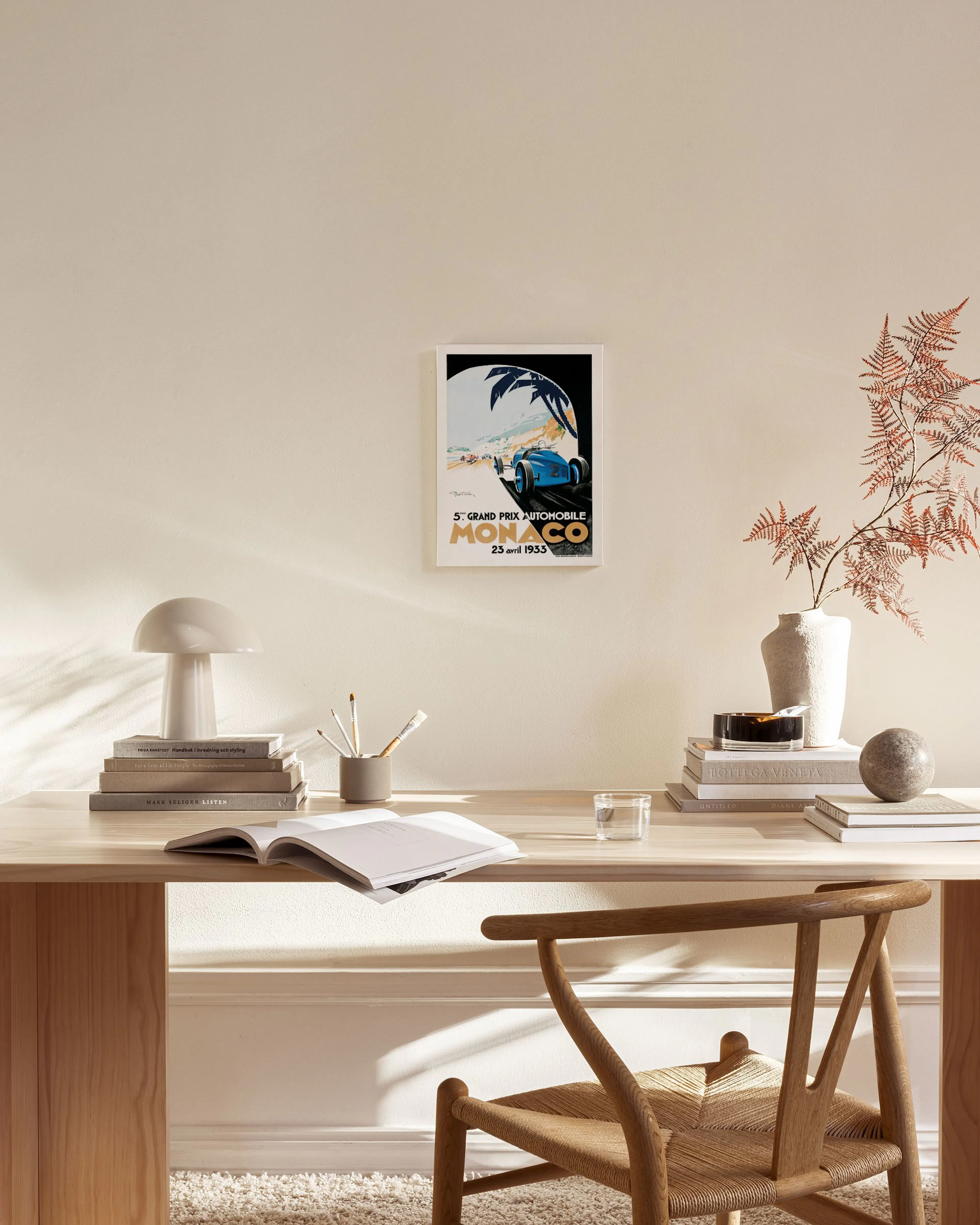 Lærred af en vintage Monaco Grand Prix plakat med en blå racerbil, der hænger i en lys stue.