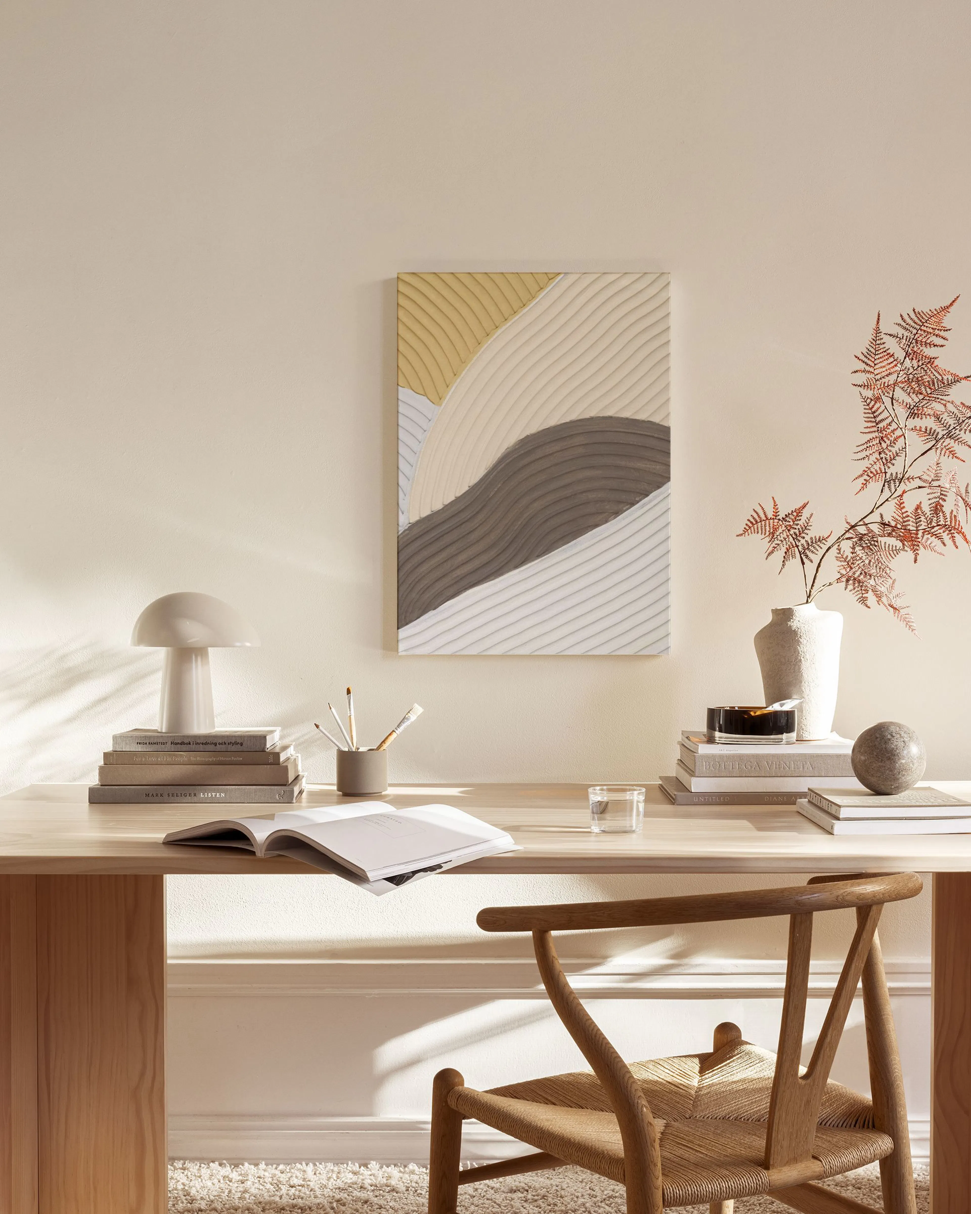 Canvas met golvende patronen in beige, grijs en bruin, hangend boven een houten dressoir in een lichte woonkamer.