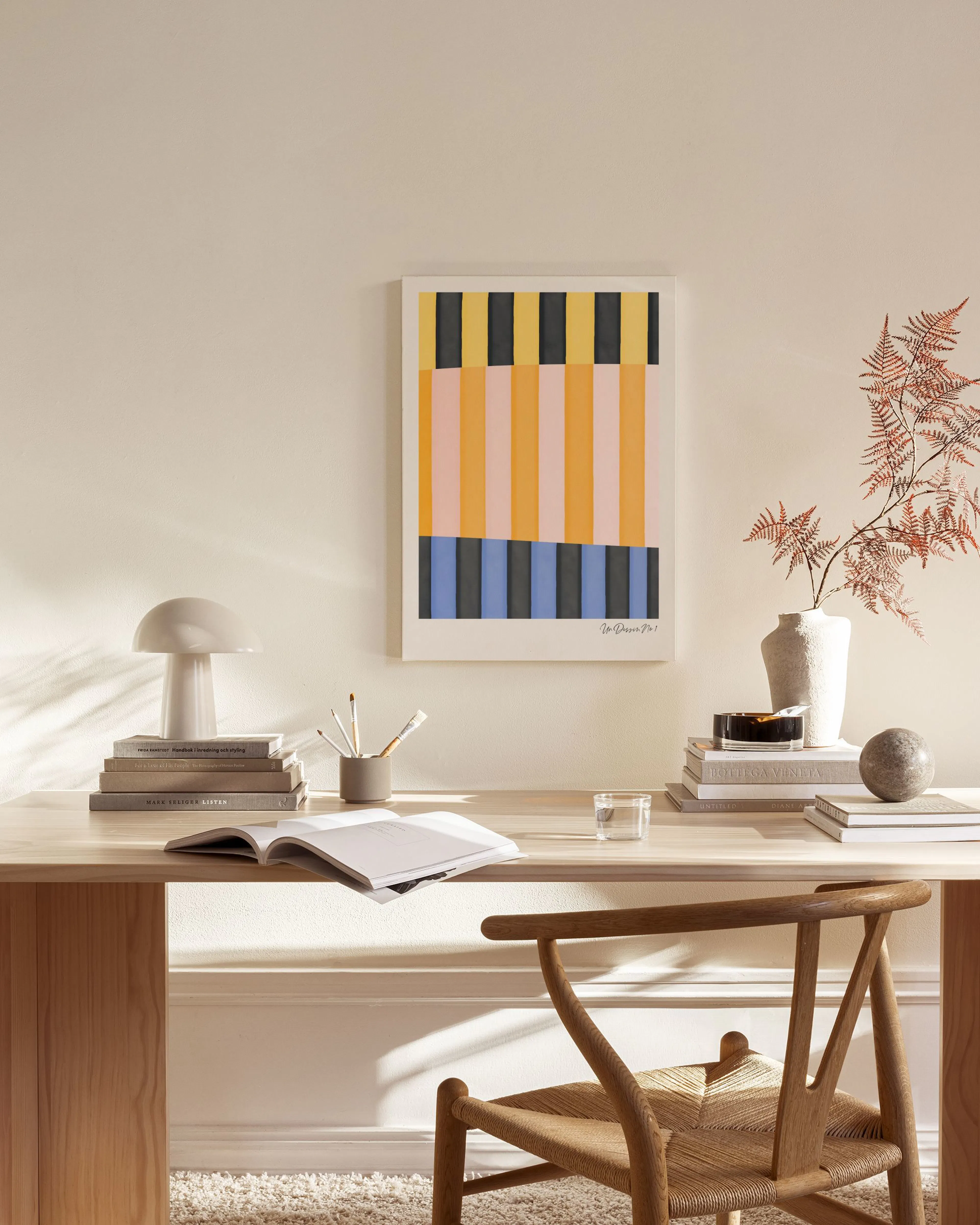 Abstract canvas print with vertical yellow, pink, and black stripes, hanging in a bright living room.