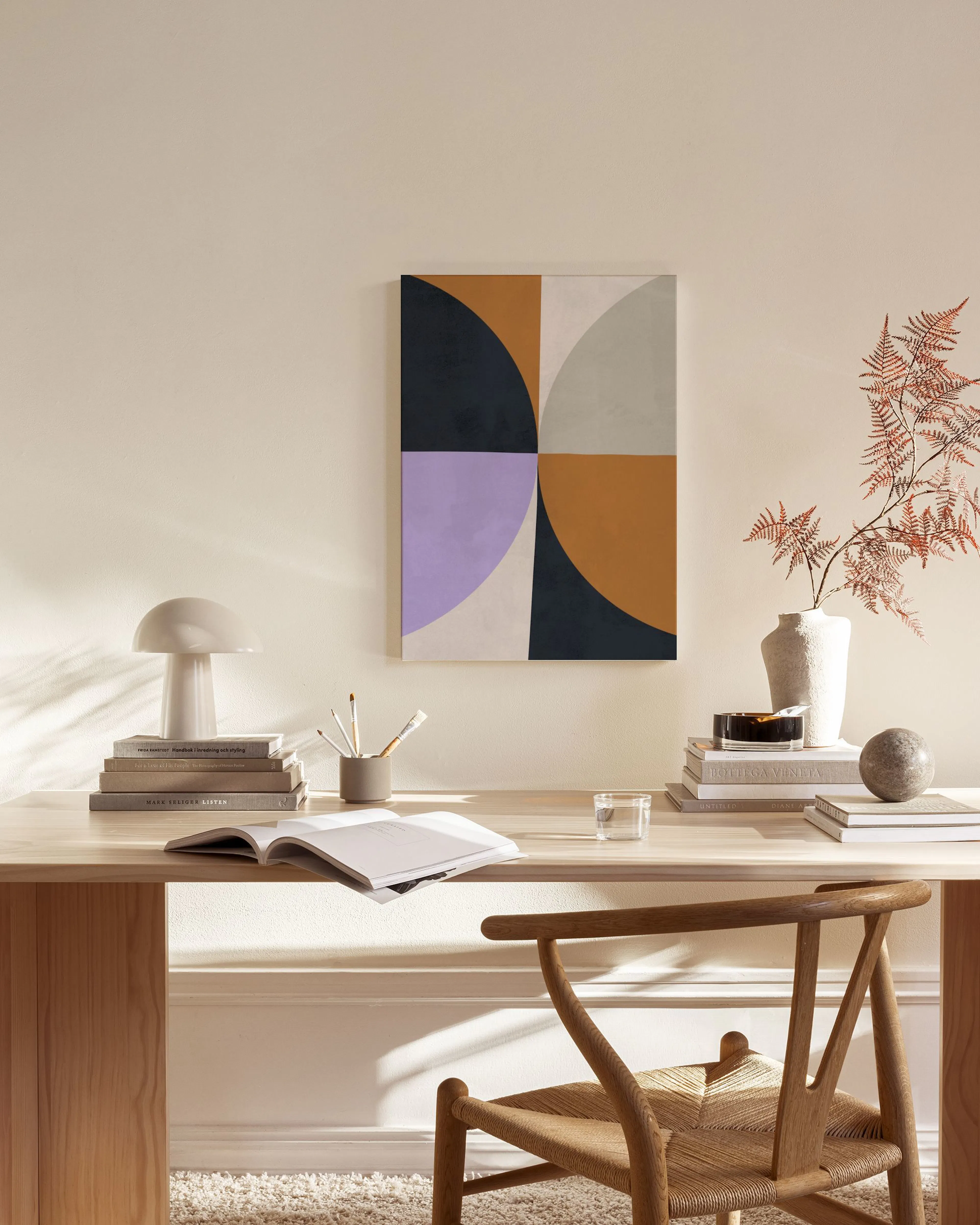 A canvas print with geometric shapes in dark blue, purple, grey, and brown, hanging in a minimalist living room above a wooden c