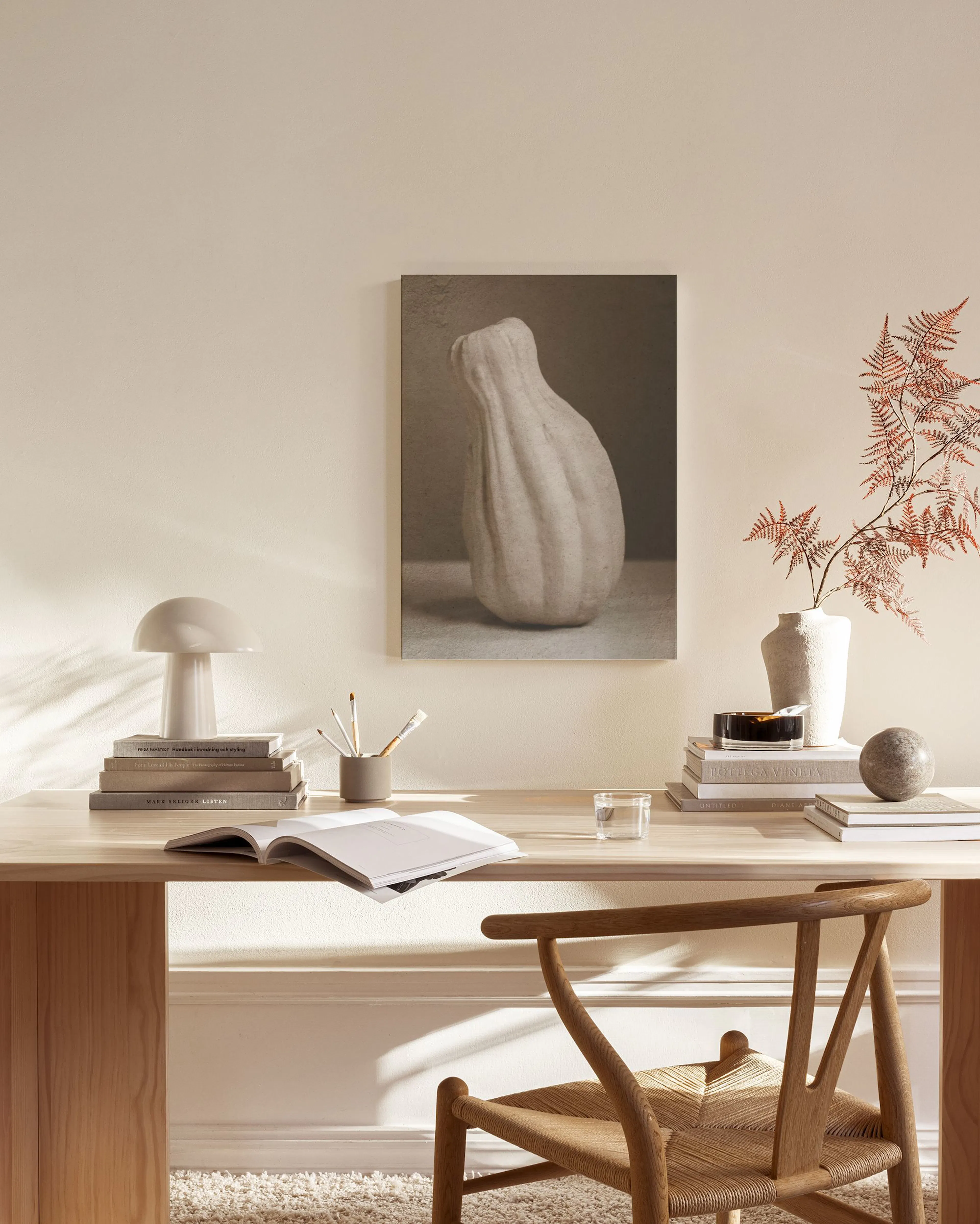 Leinwandbild einer beigen Kürbis-Skulptur, hängend über einem Sideboard in einem minimalistischen Wohnzimmer.