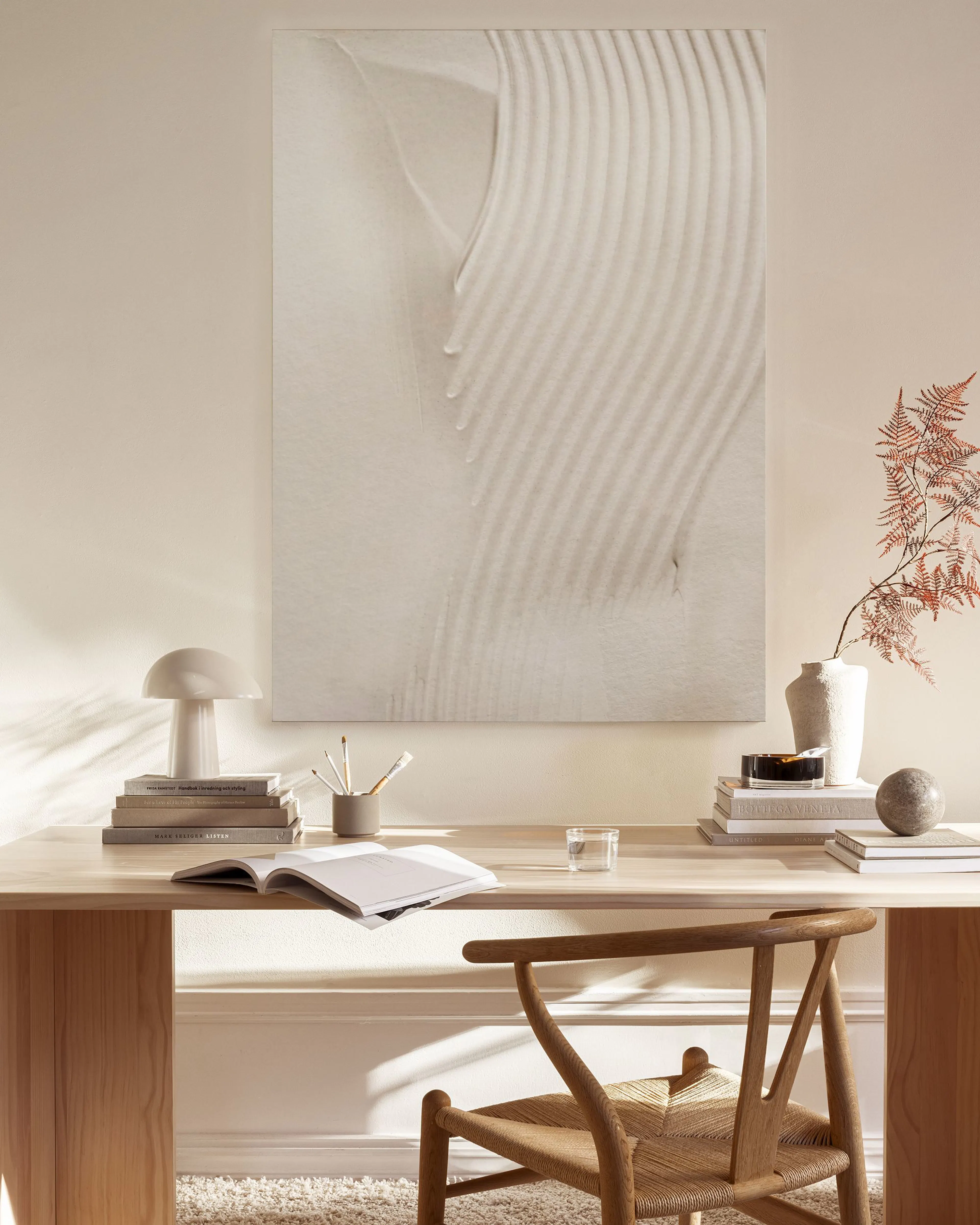 A canvas print of white rippled sand dunes, hanging above a wooden console in a neutral-toned living room.