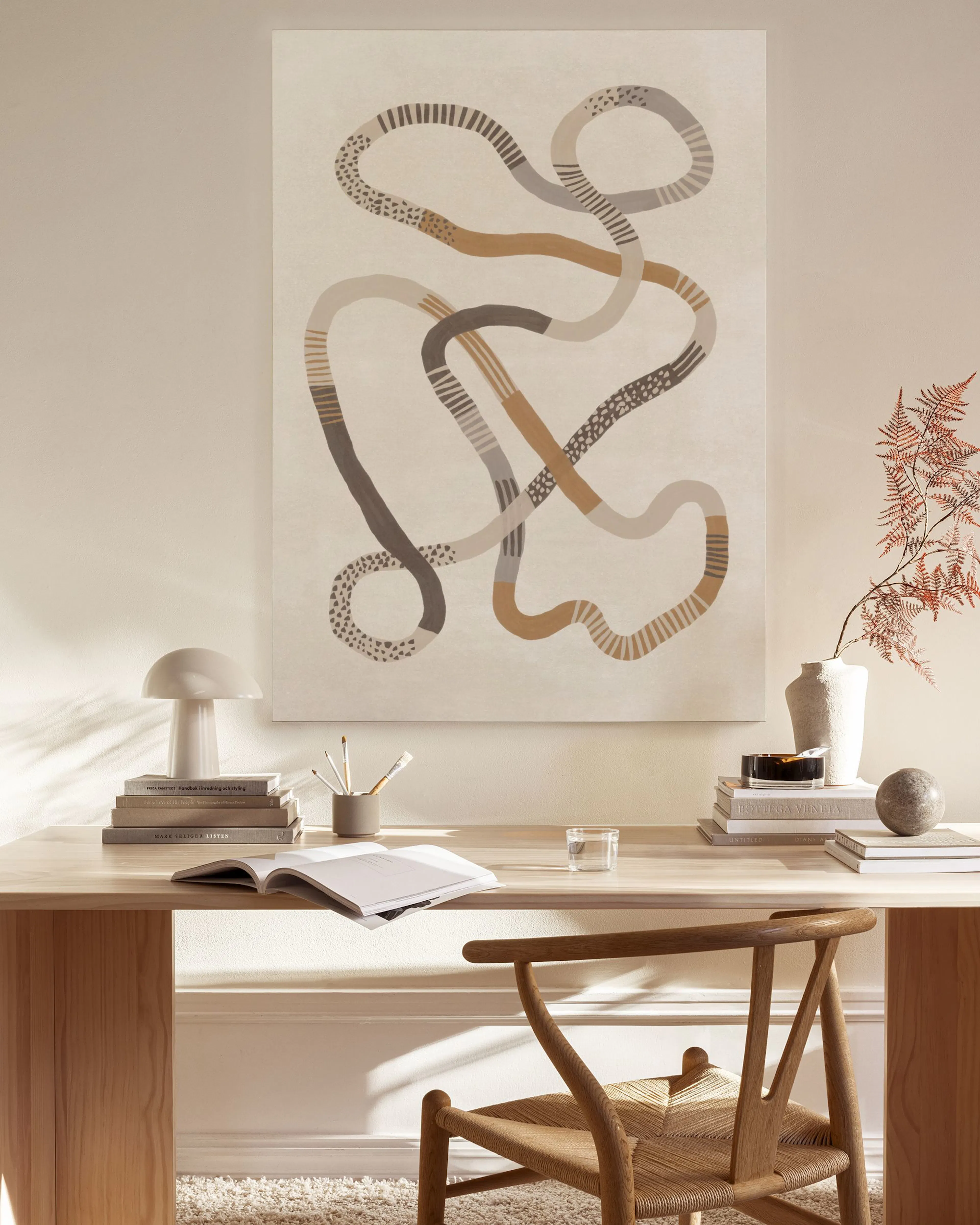 Abstract canvas print with intertwining brown and grey organic lines, dots, and stripes, displayed in a neutral living room.