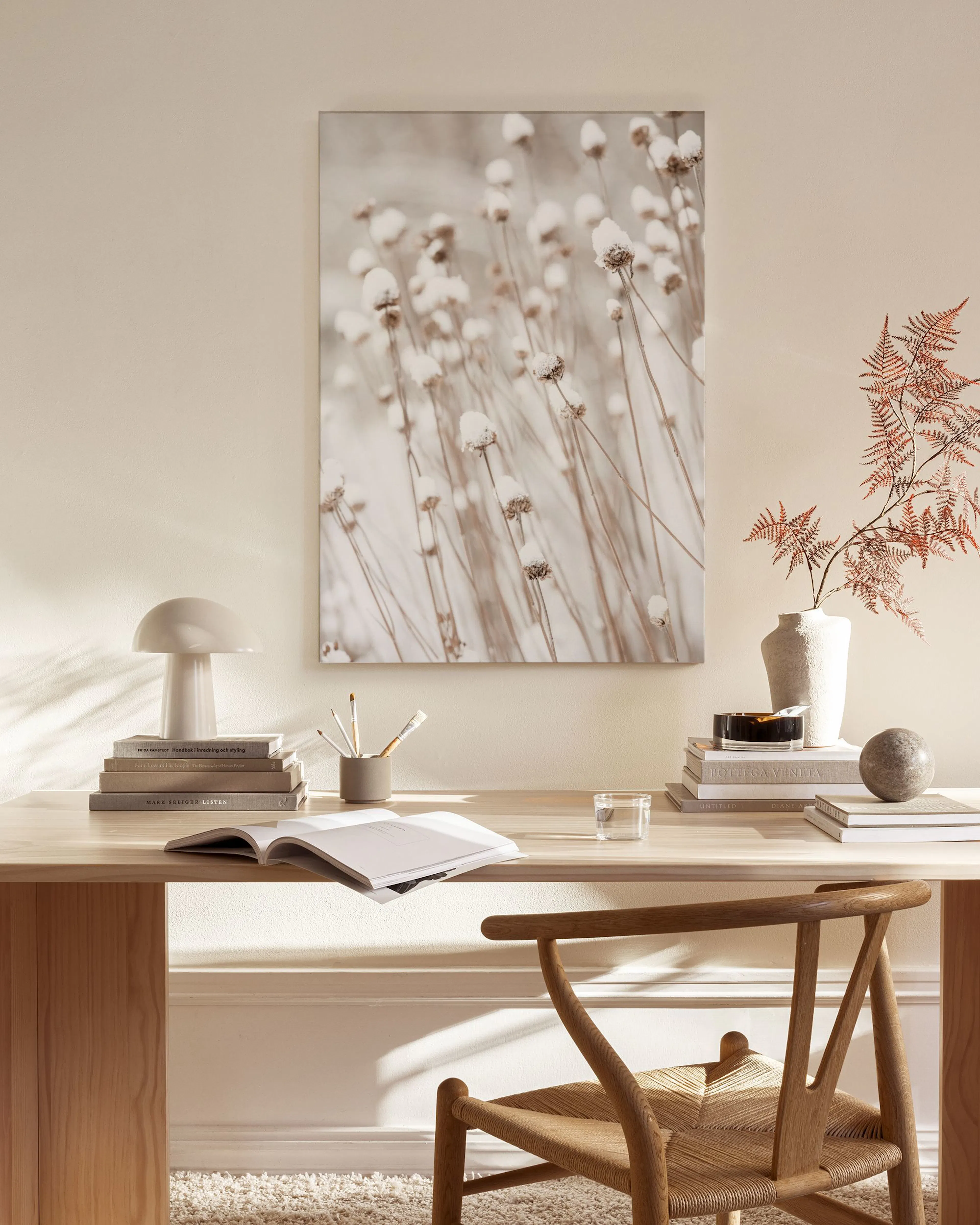 Leinwandbild mit winterlichen Gräsern in Beigetönen, hängt über einem Sideboard im Wohnzimmer.