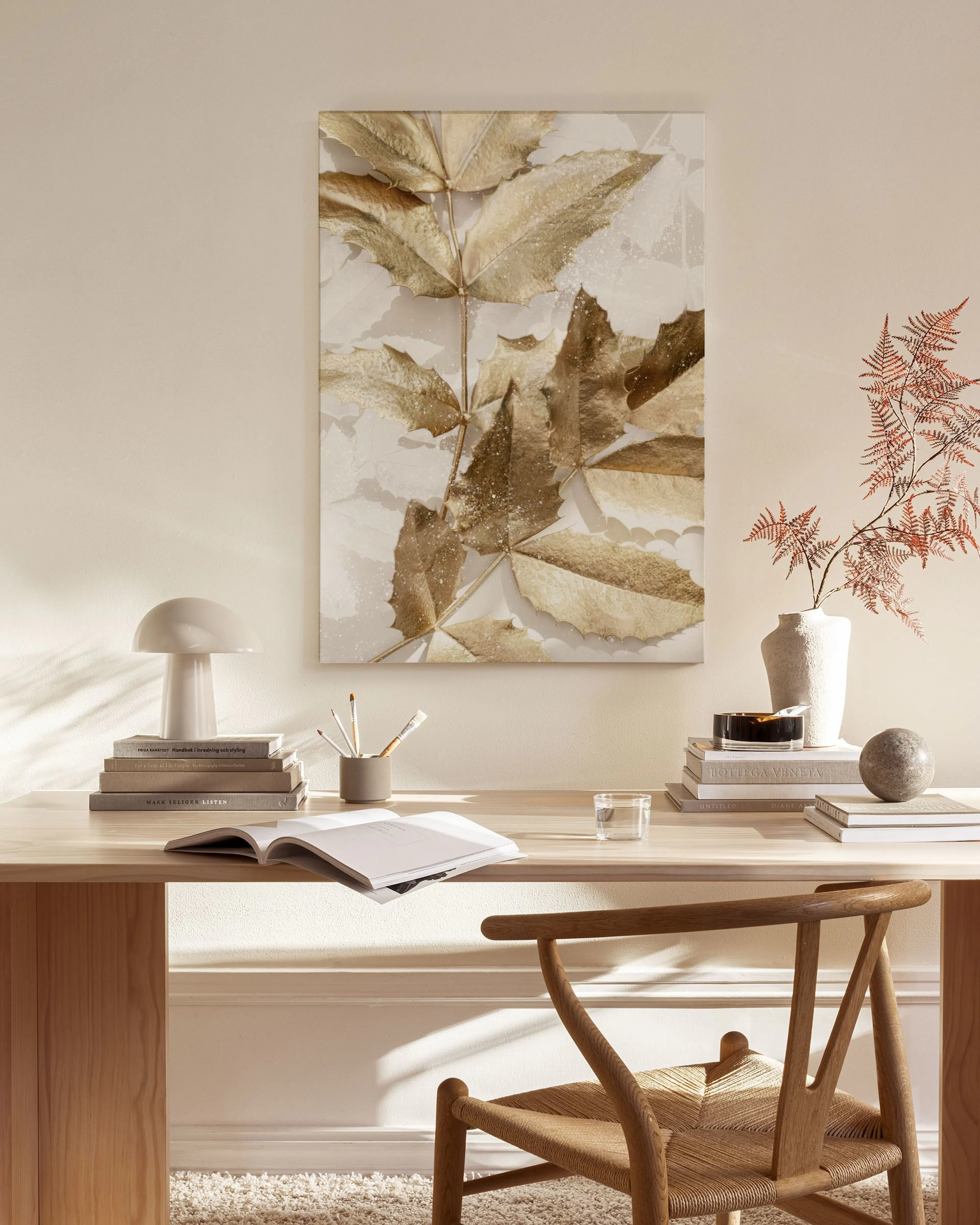 Leinwandbild mit goldenen Herbstblättern, hängend in einem hellen Wohnzimmer über einem Holztisch.