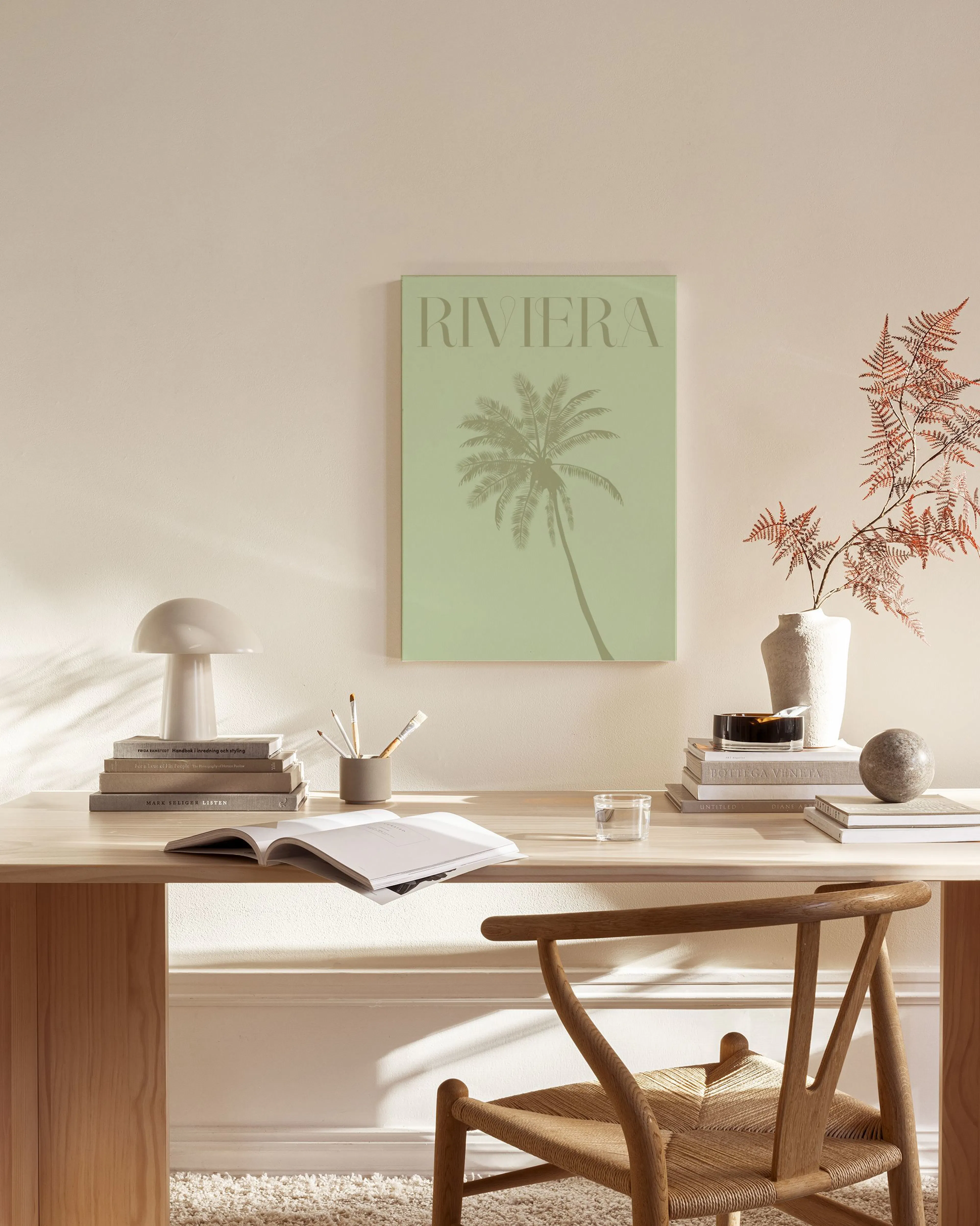 Canvas met Riviera en een palmboom op een lichte achtergrond, hangend in een neutrale woonkamer boven een dressoir.