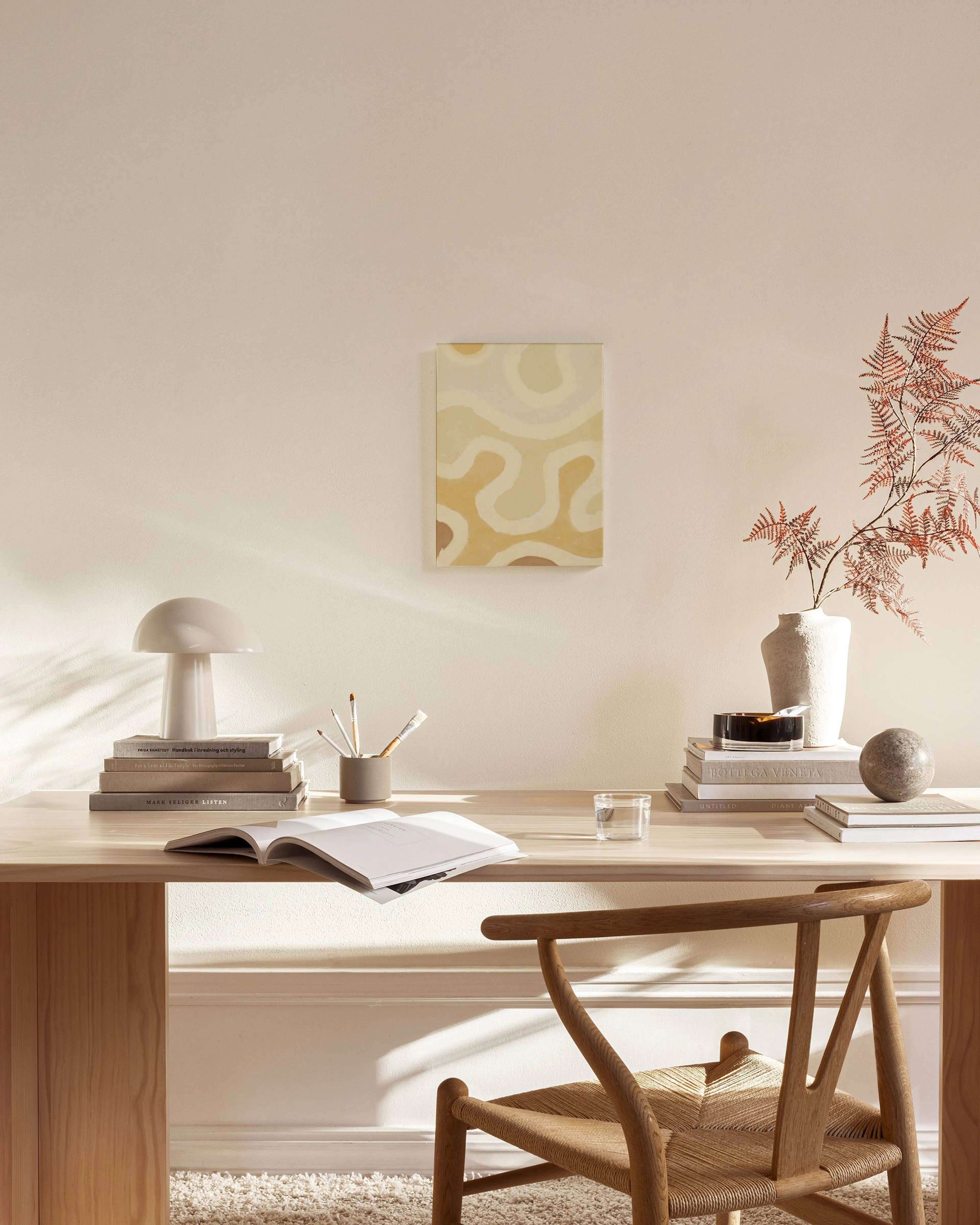 Canvas met organische, golvende vormen in beige en geel, hangend in een neutrale woonkamer.
