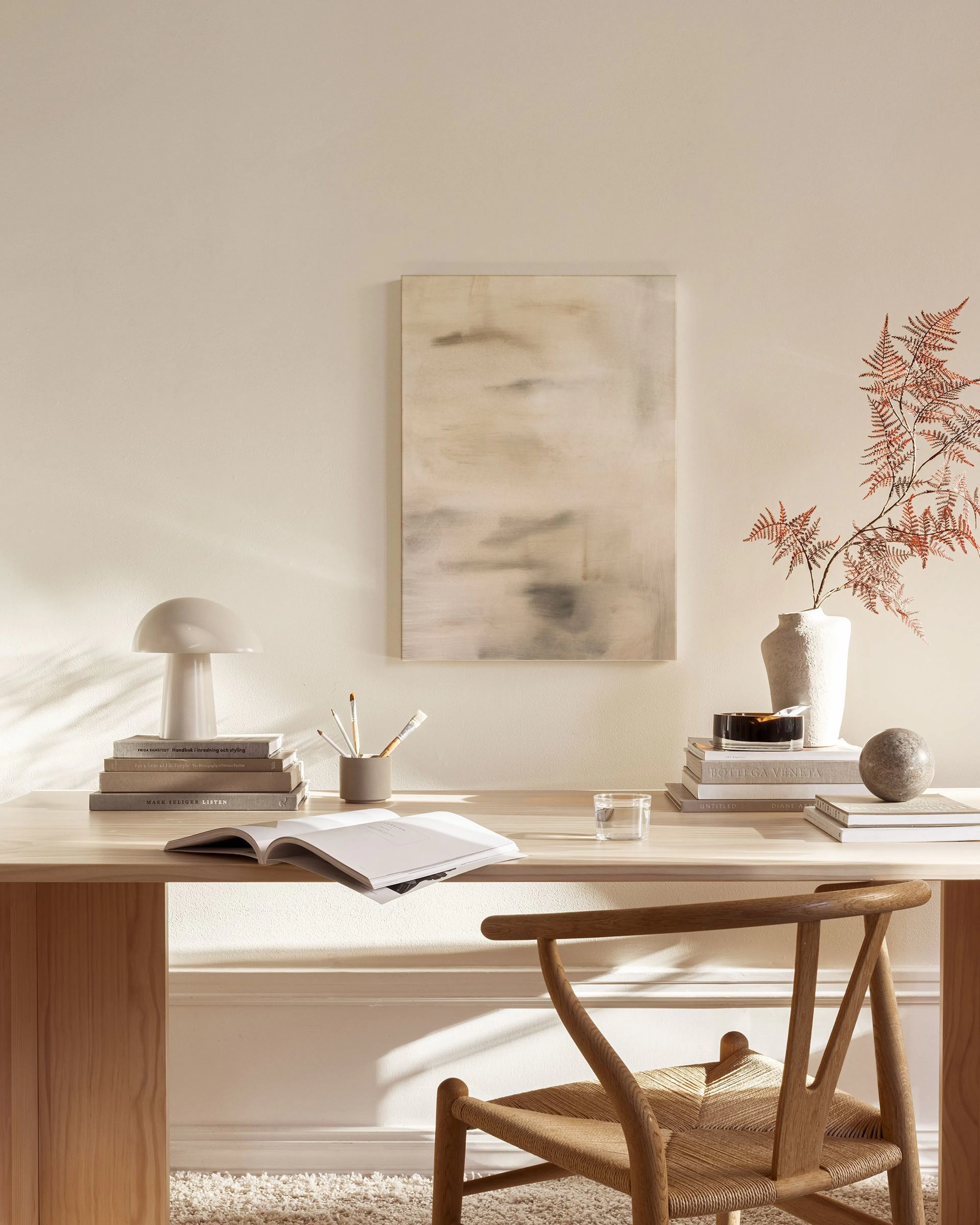 Lærred med beige og grå nuancer med bløde overgange, hængende over en bænk i en stilfuld stue.