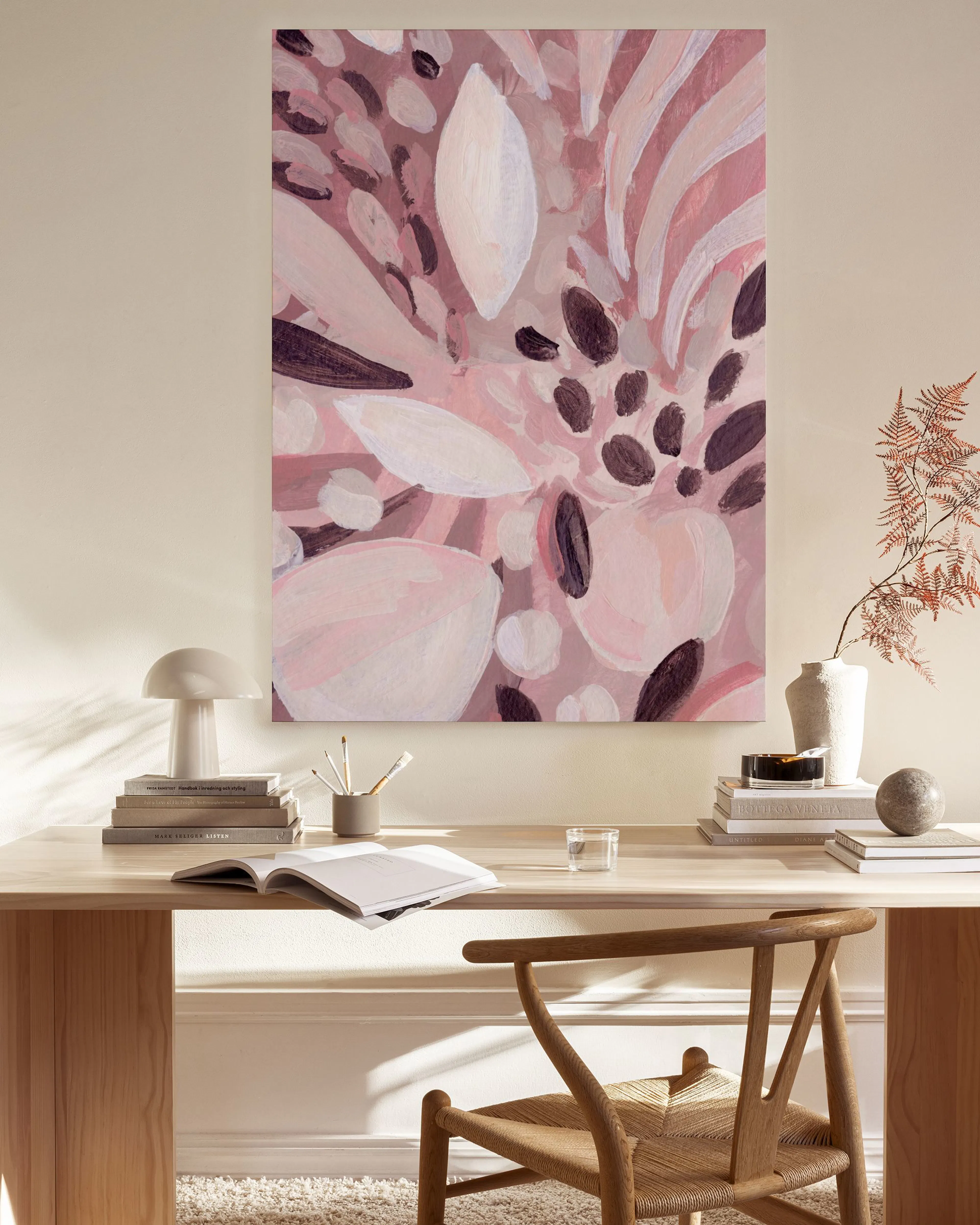 Lienzo con motivos florales abstractos en tonos rosas y morados oscuro, colgado sobre un mueble bajo de madera en un salón moder