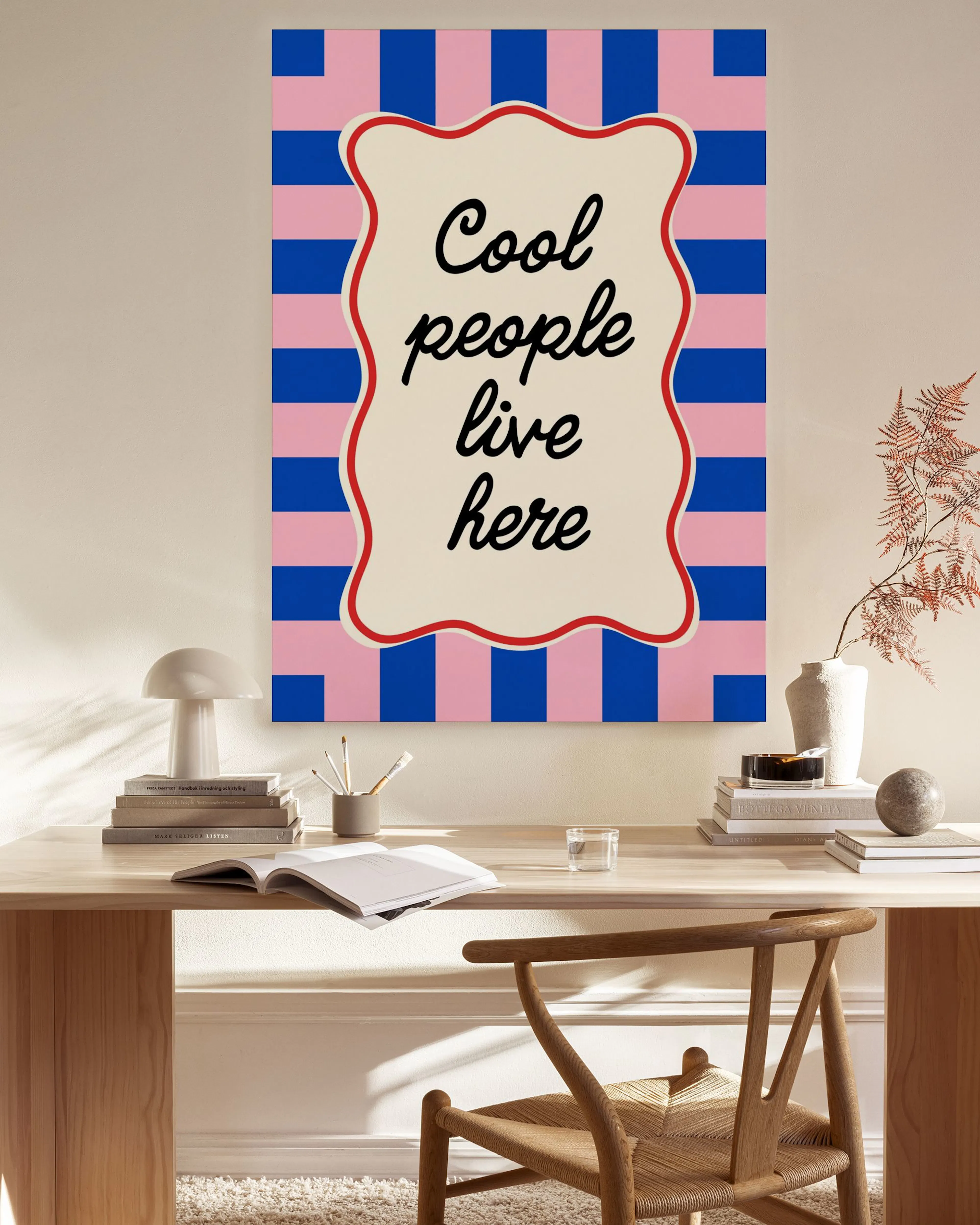 Leinwandbild mit rosa und blauen Streifenmuster und dem Spruch Cool people live here in einem modernen Wohnzimmer.